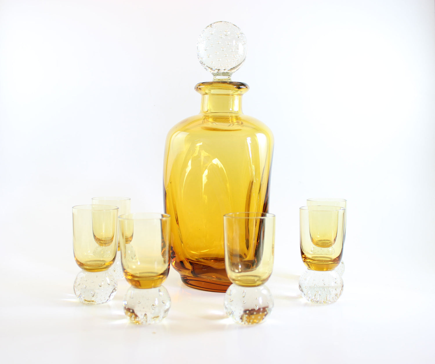 Set of amber pinched glass decanter and six glasses on a white background
