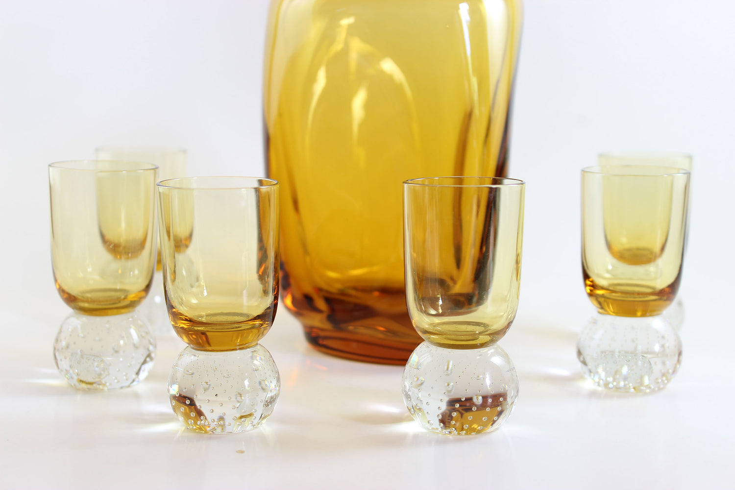Set of amber pinched glass decanter and six glasses on a white background