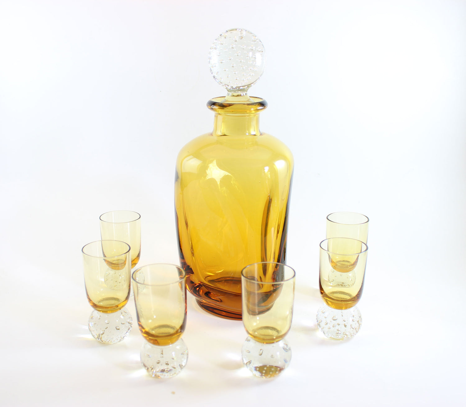 Set of amber pinched glass decanter and six glasses on a white background