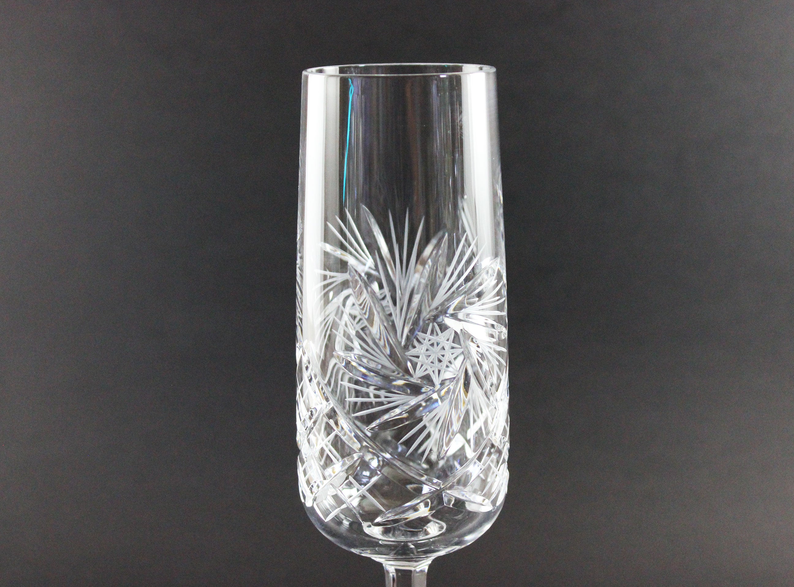 Crystal champagne flute with intricate cut design on a dark background