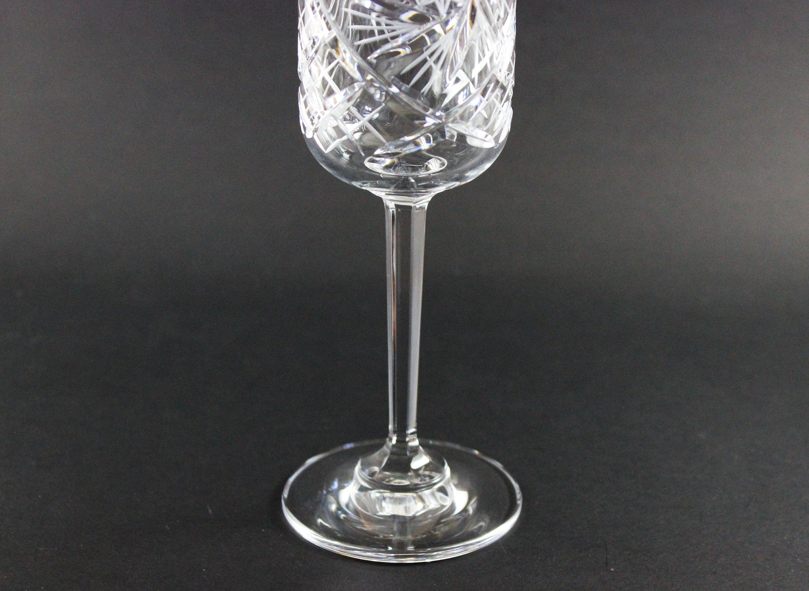 Crystal wine glass with intricate cut design on a black background