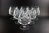 Set of six crystal glasses with intricate designs on a black background