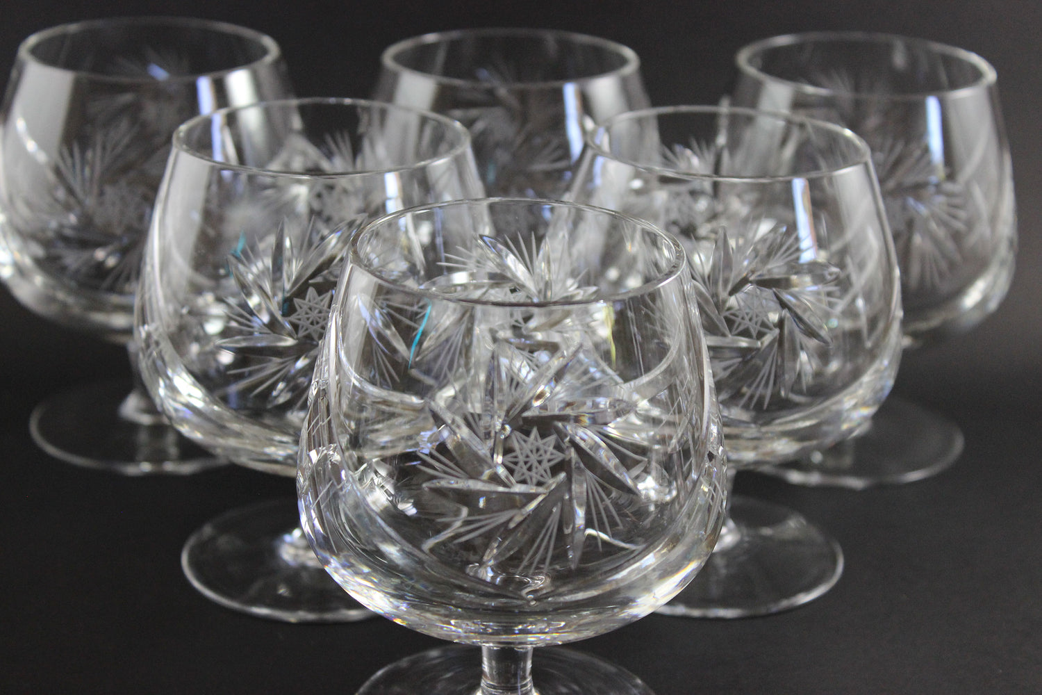 Set of crystal glasses with intricate designs on a dark background