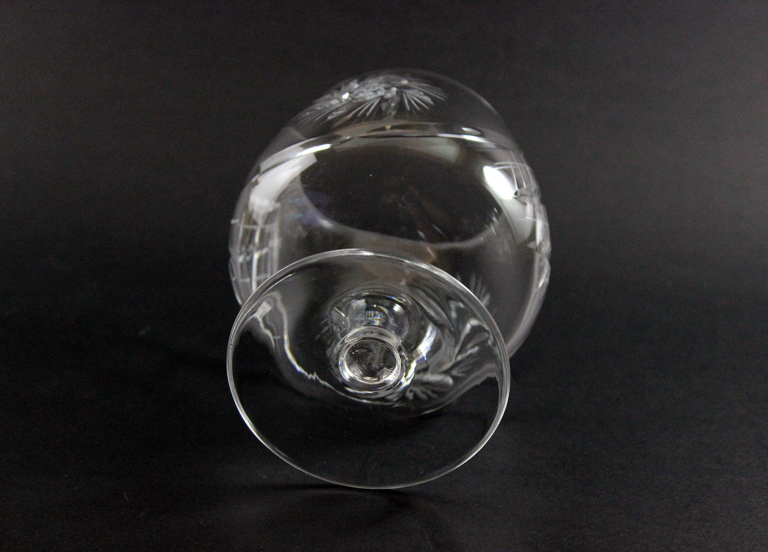 Clear glass goblet with engraved design on a black background