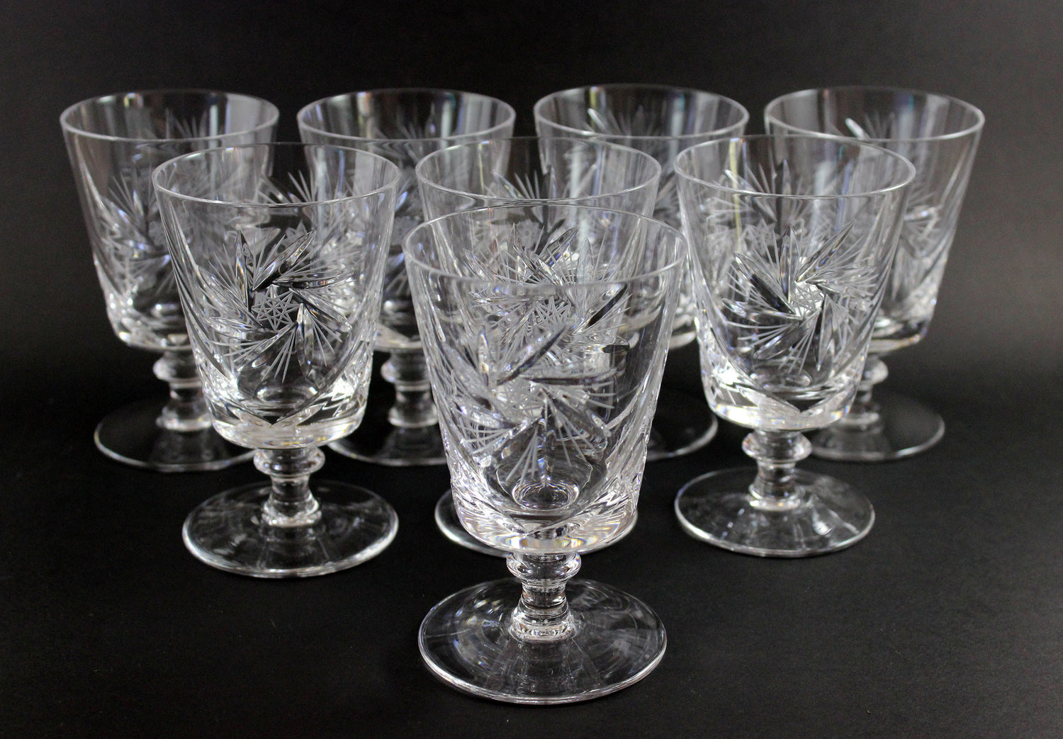 Set of crystal glasses with engraved designs on a black background