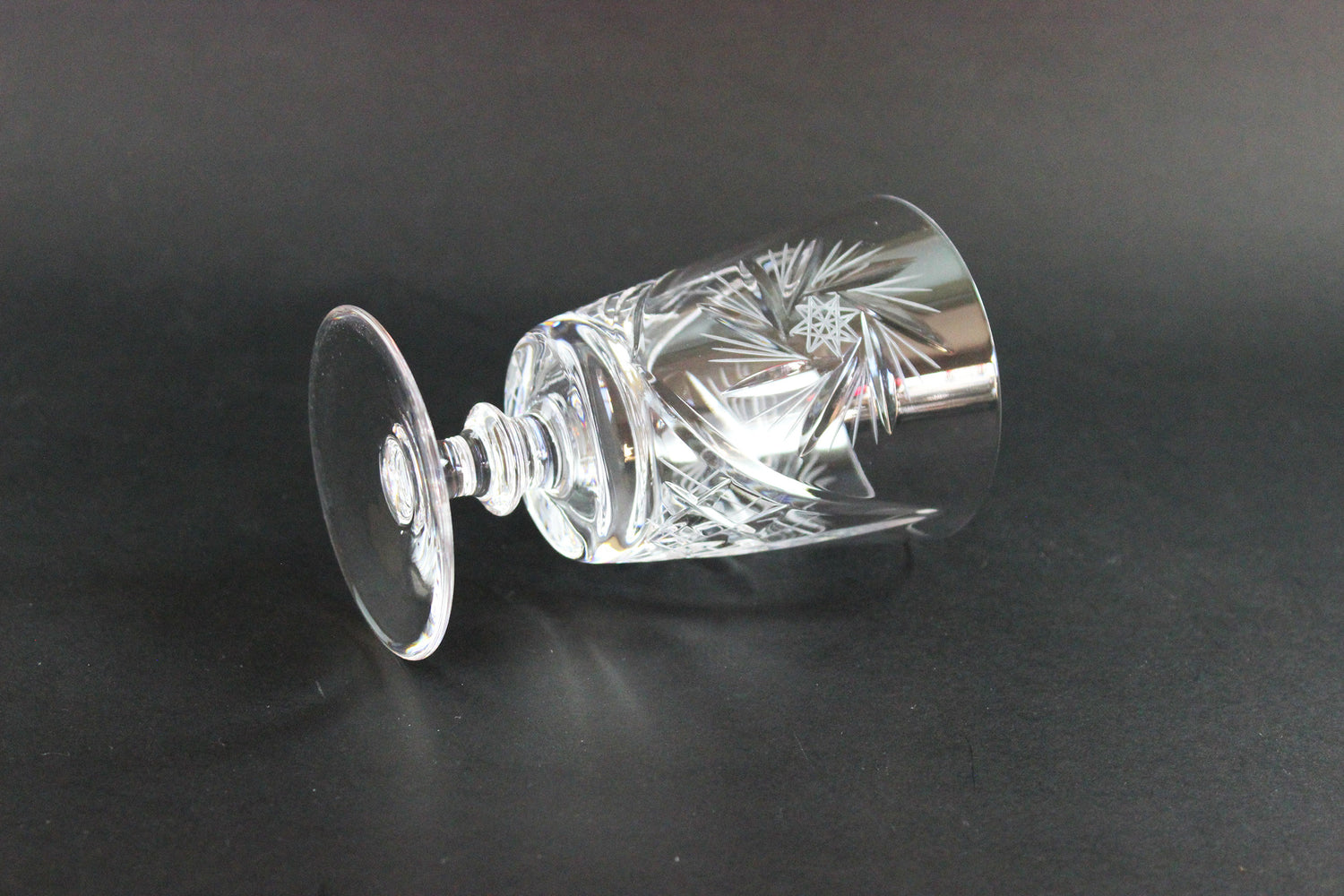 Crystal wine glass with intricate cut patterns on a black background