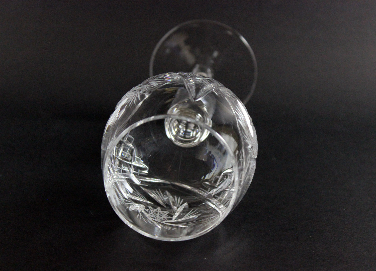 Clear crystal wine goblet with intricate designs on a black background