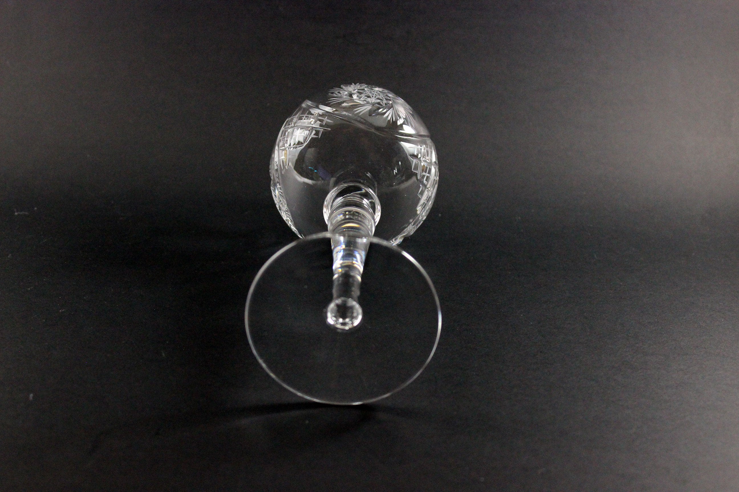 Clear glass wine goblet with intricate design on a black background
