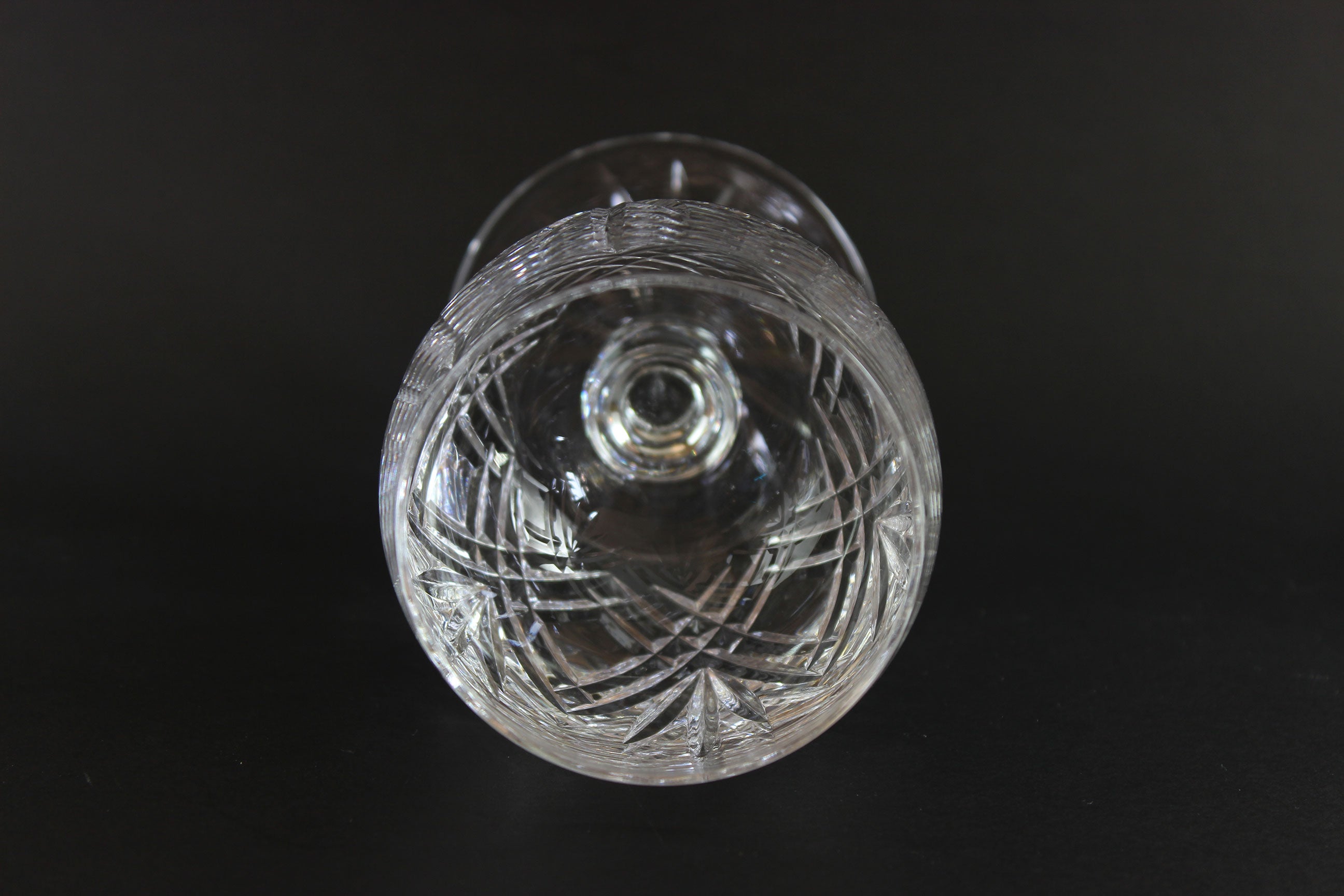 Cut crystal wine glass with intricate cut patterns on a black background