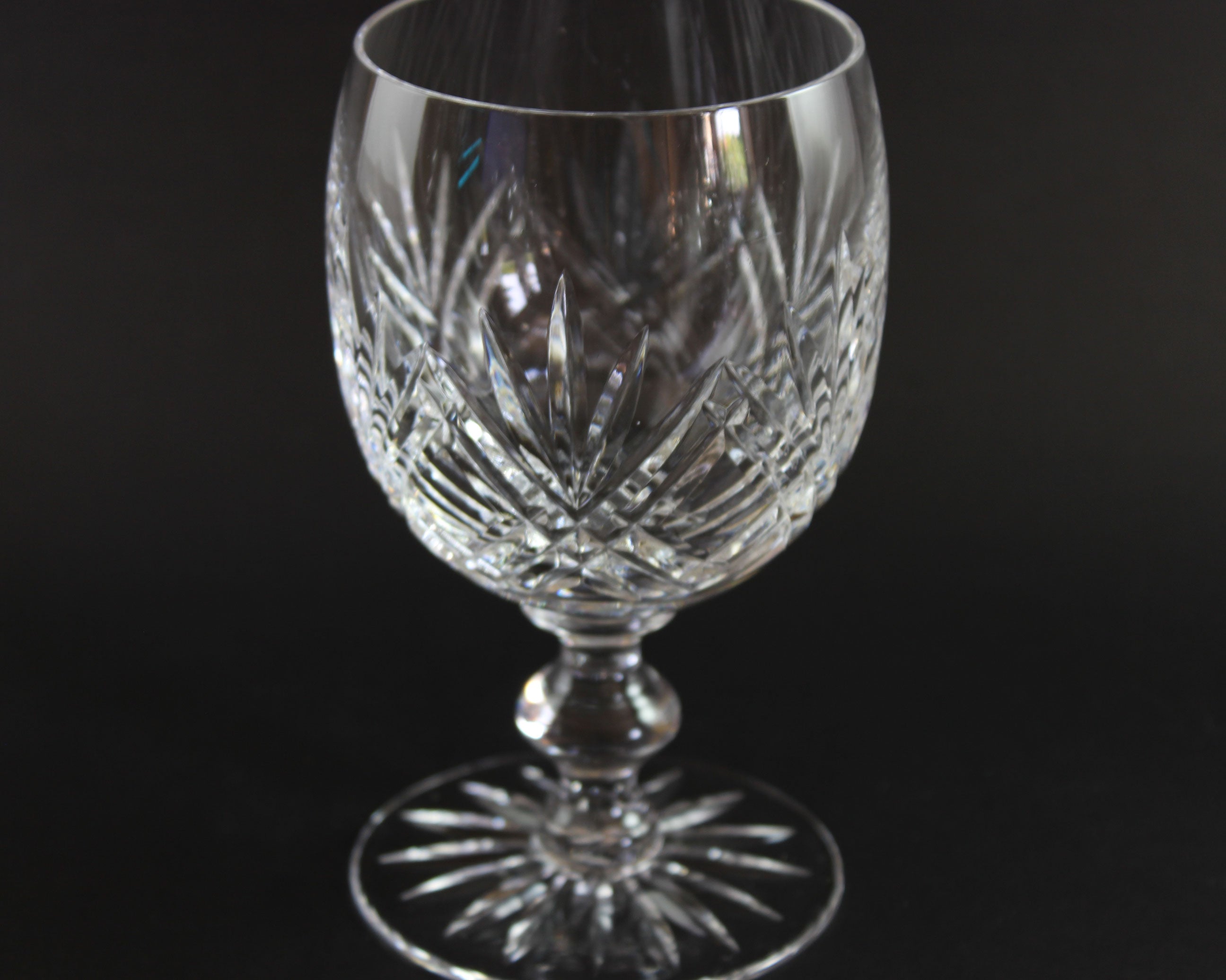Crystal wine glass with intricate cut patterns on a black background