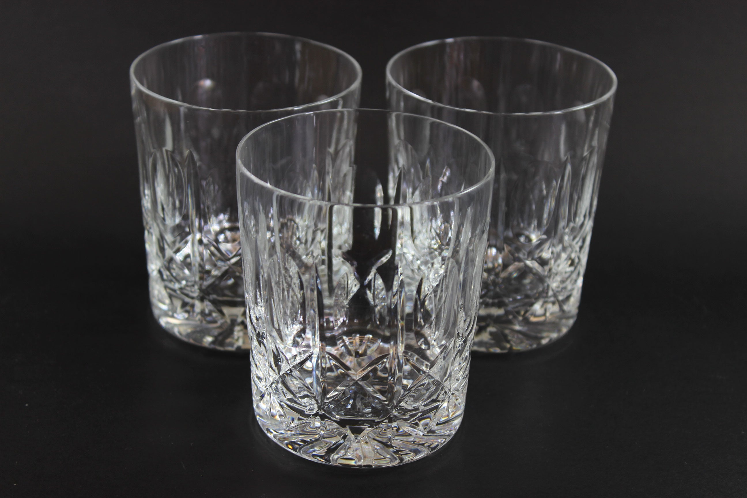 Three crystal glasses with cut patterns on a black background