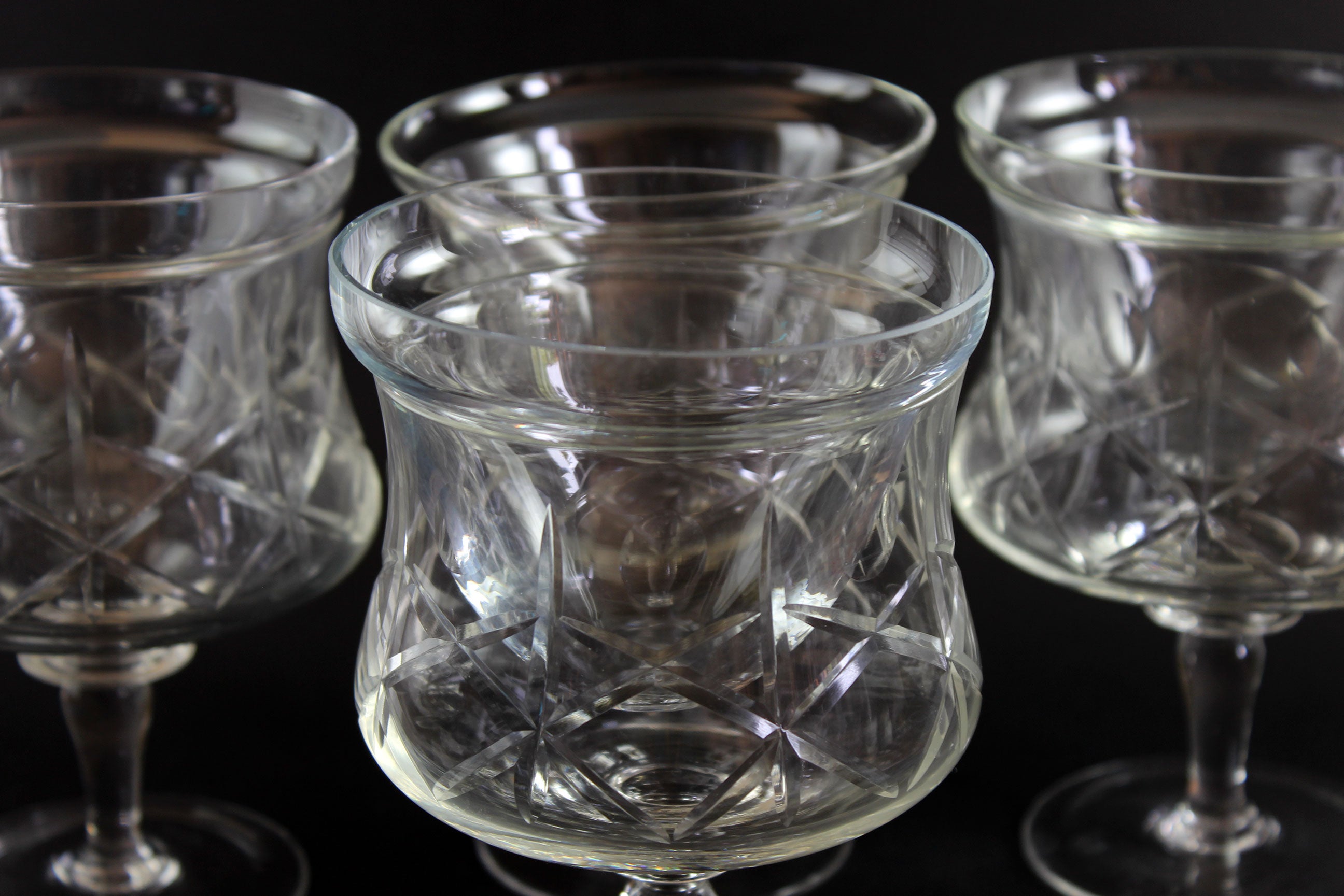 Set of clear glass tumblers with cross and olive cut pattern on a dark background