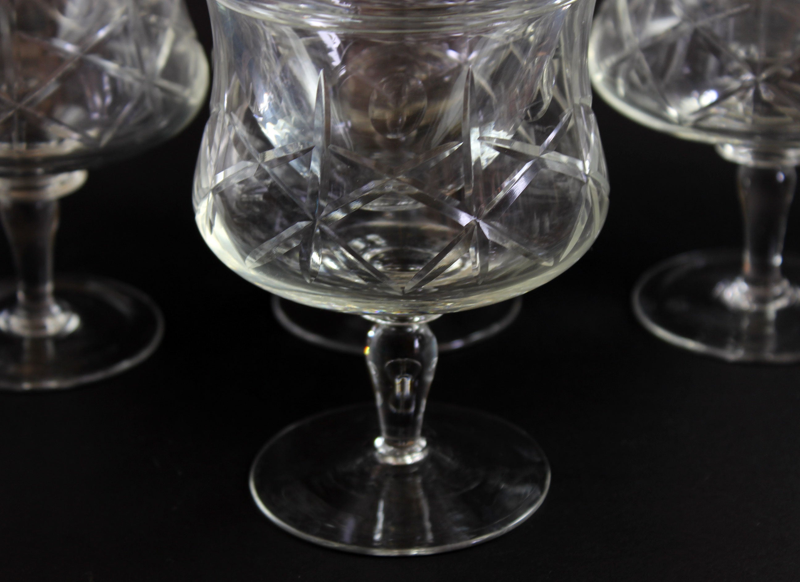 Set of crystal glasses with intricate cut patterns on a black background