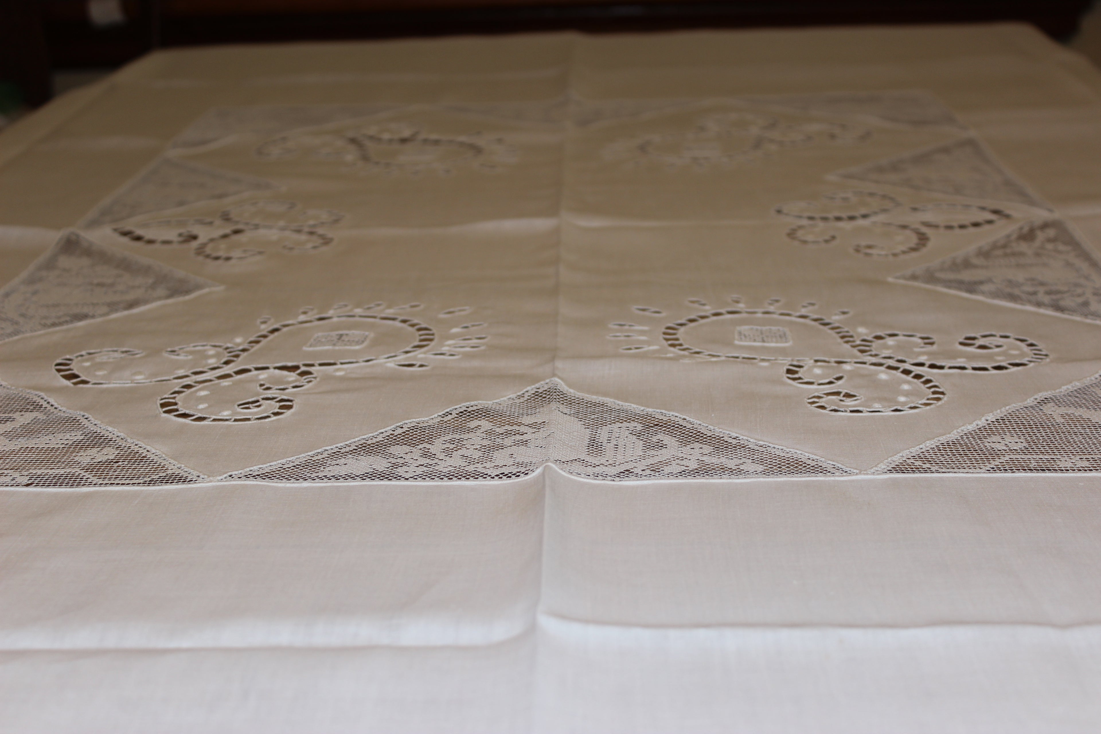 Beige lace tablecloth with intricate patterns on a white background