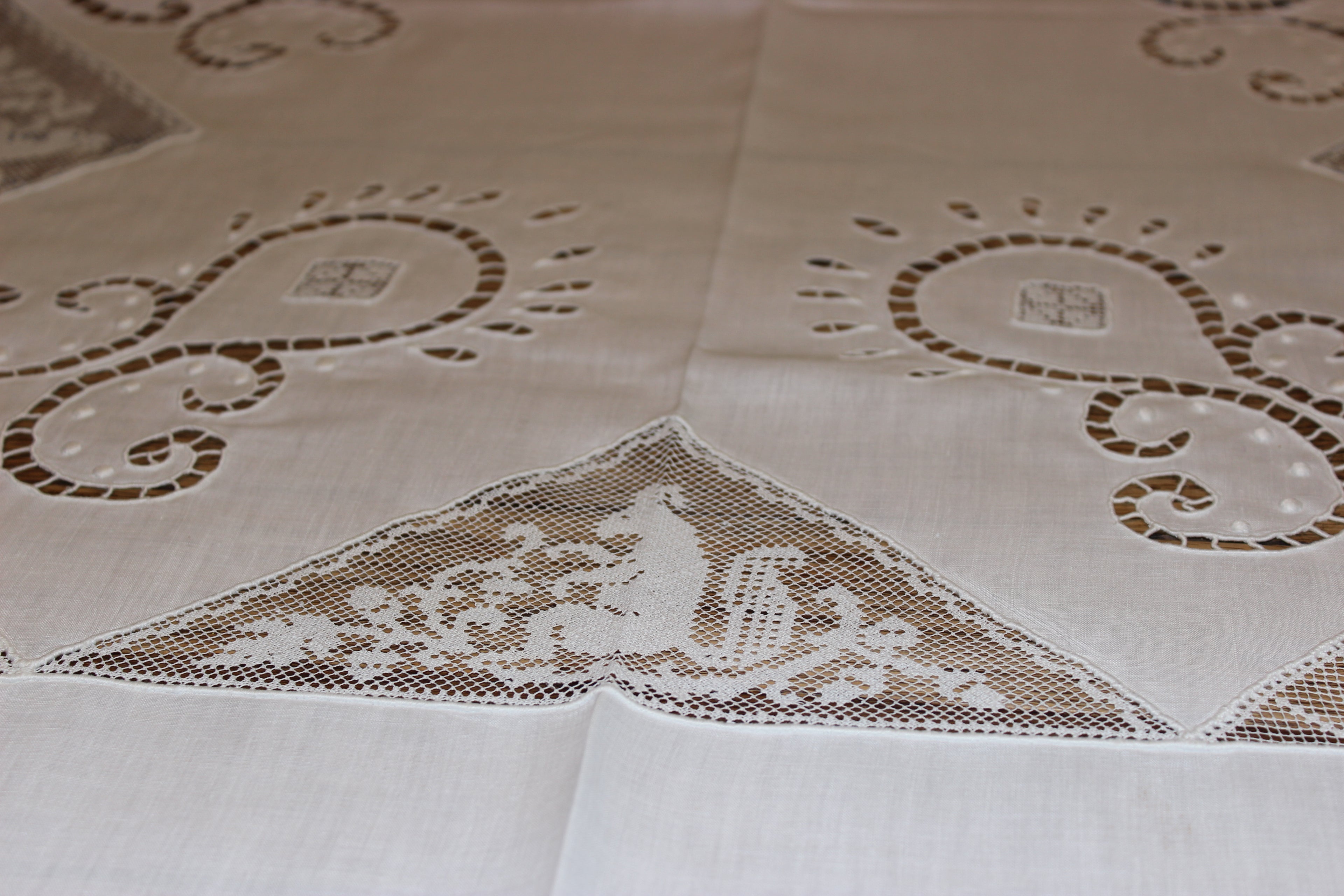 Decorative tablecloth with lace detailing and geometric patterns on a beige background