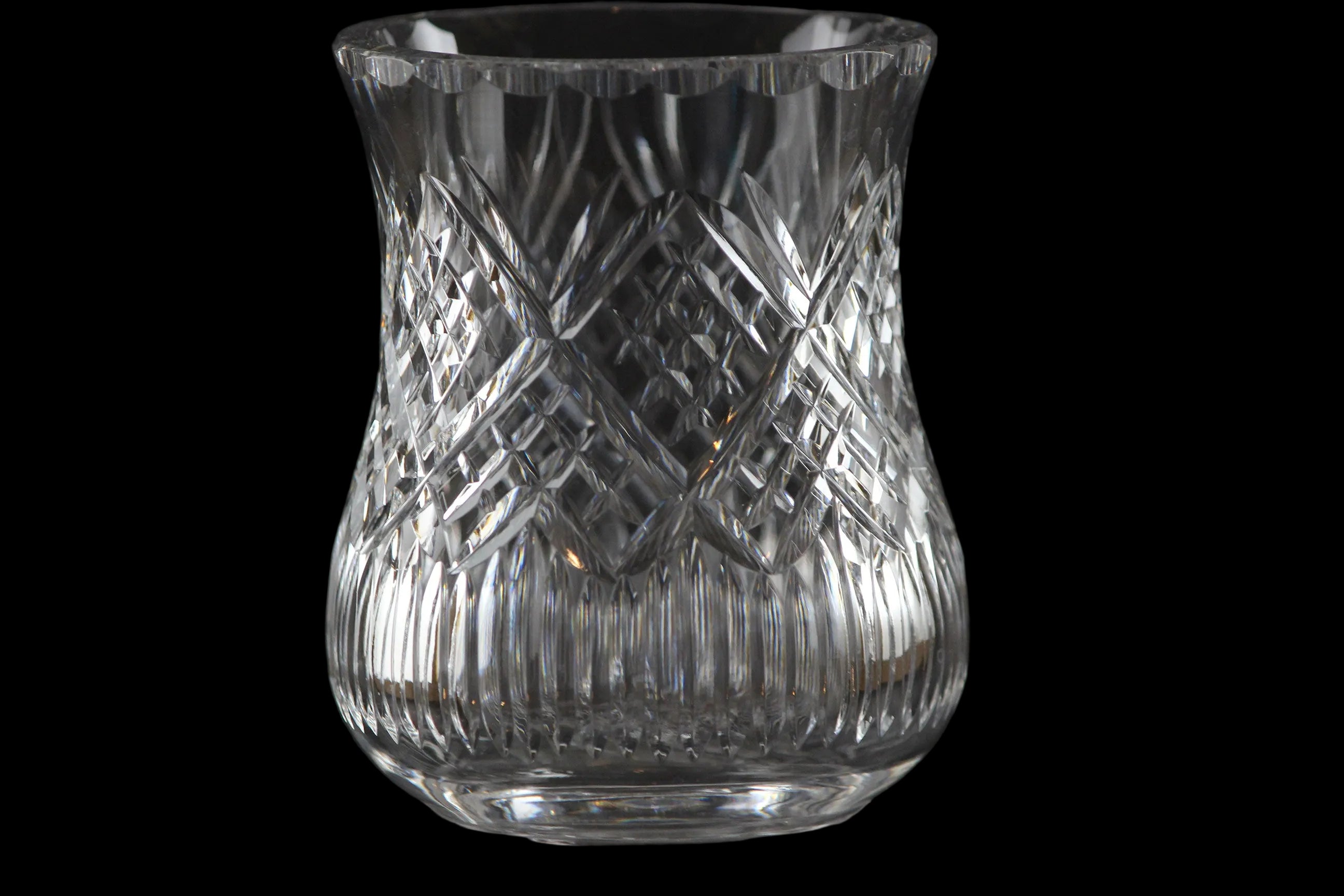 Clear glass candle holder with intricate patterns on a black background