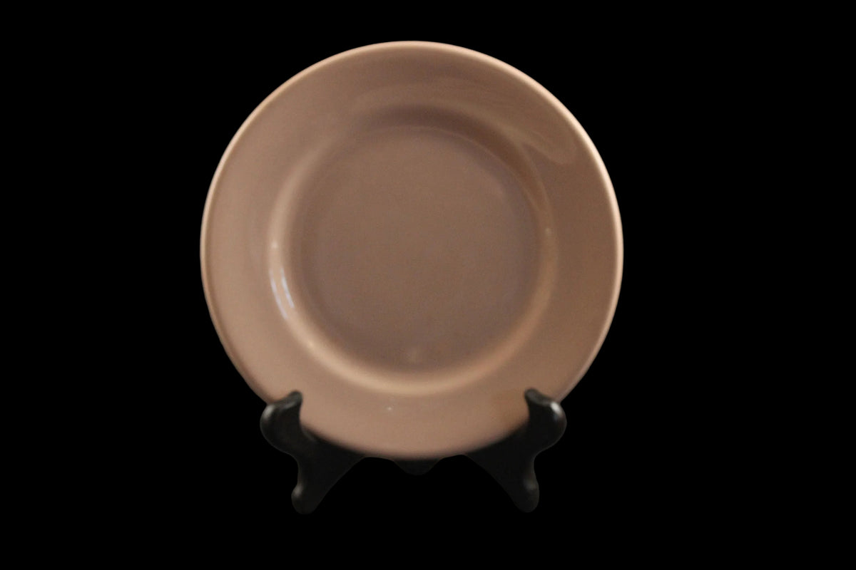 Pink ceramic plate on a black stand against a dark background