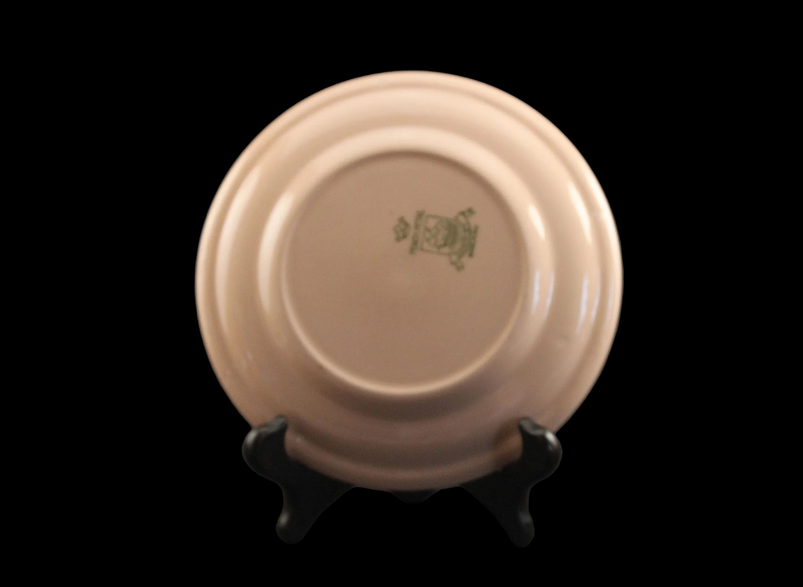 Pink plate with a logo on a black stand against a dark background