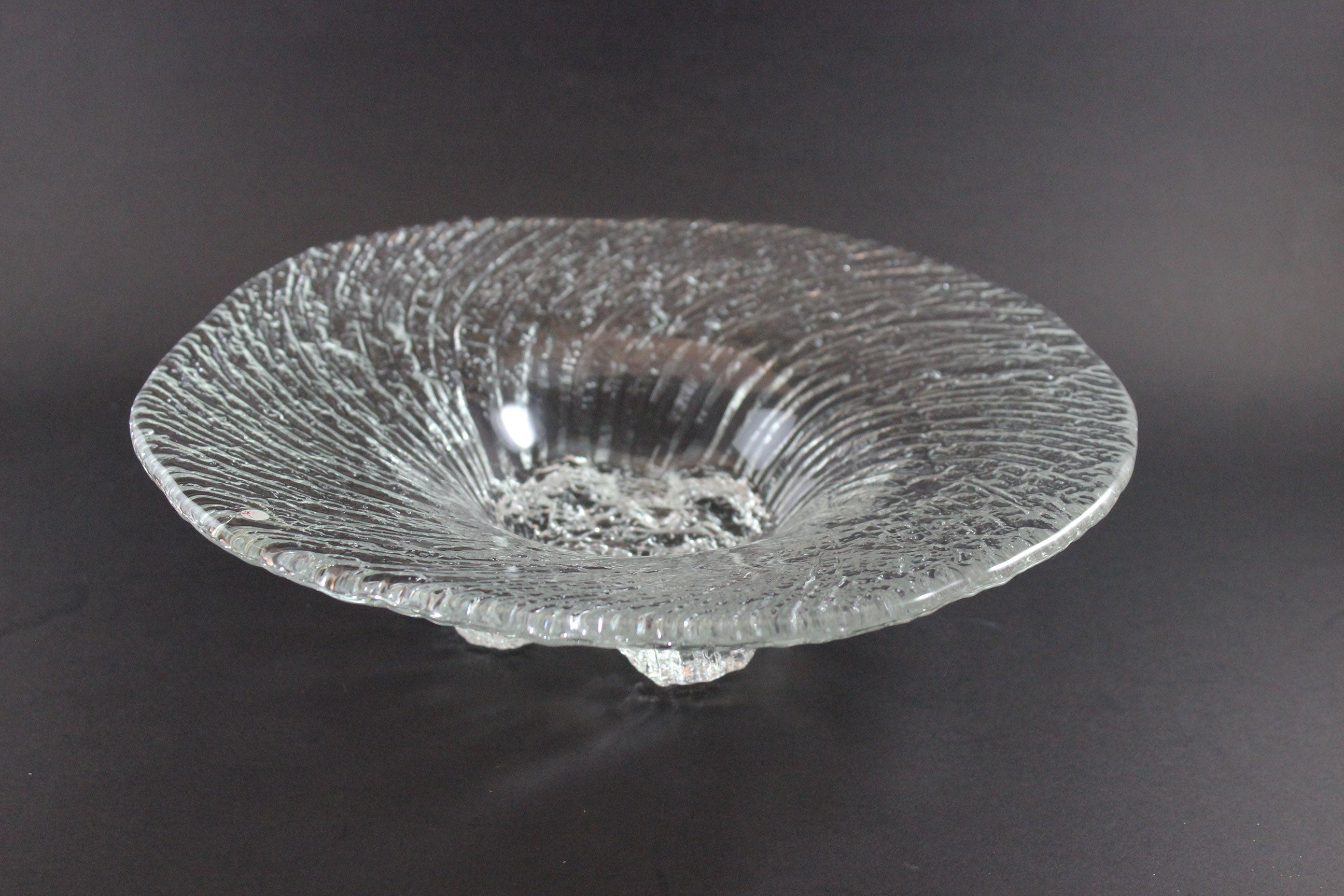 Clear glass bowl with textured surface on a dark background