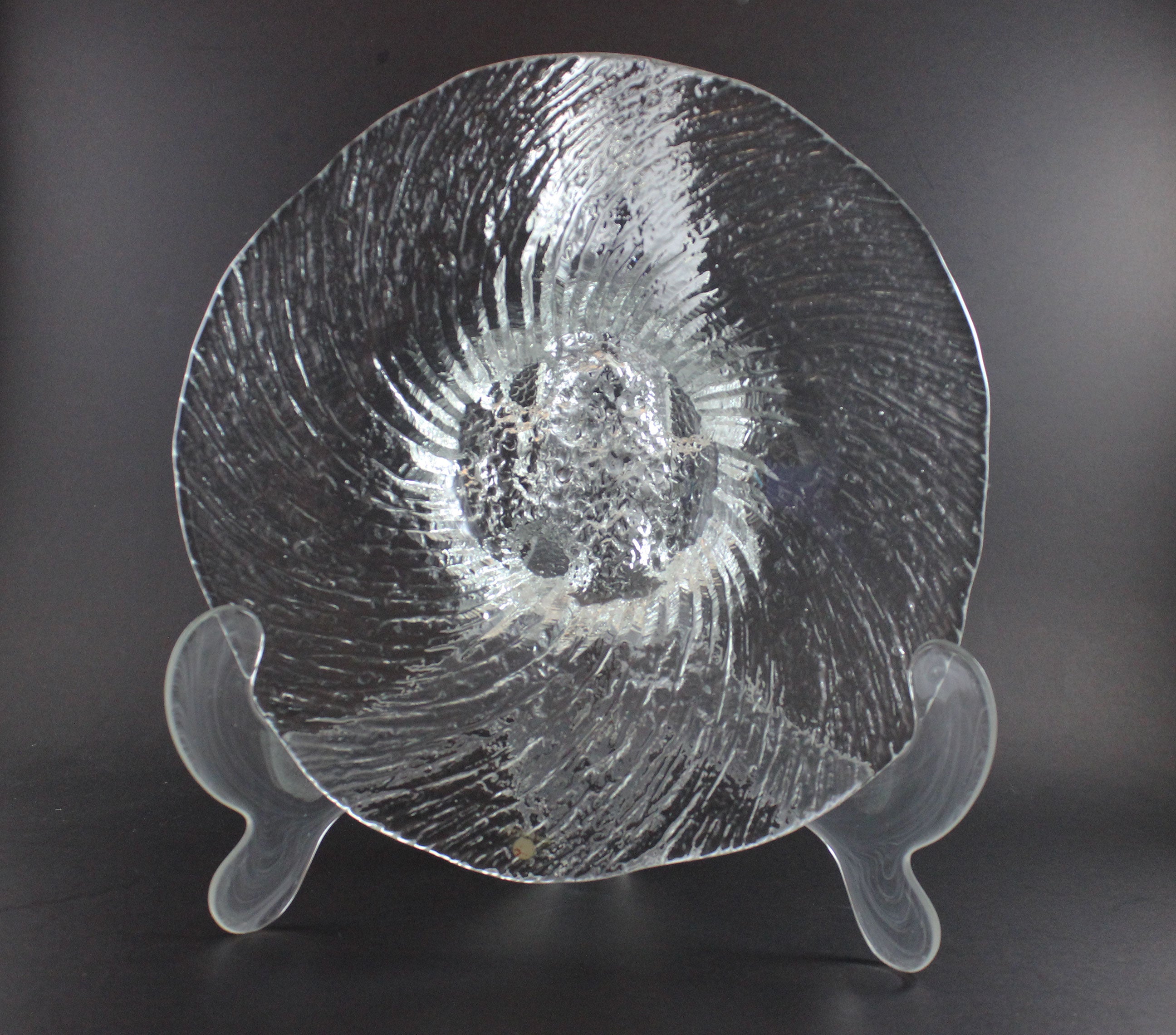 Clear glass footed bowl with textured surface on a dark background