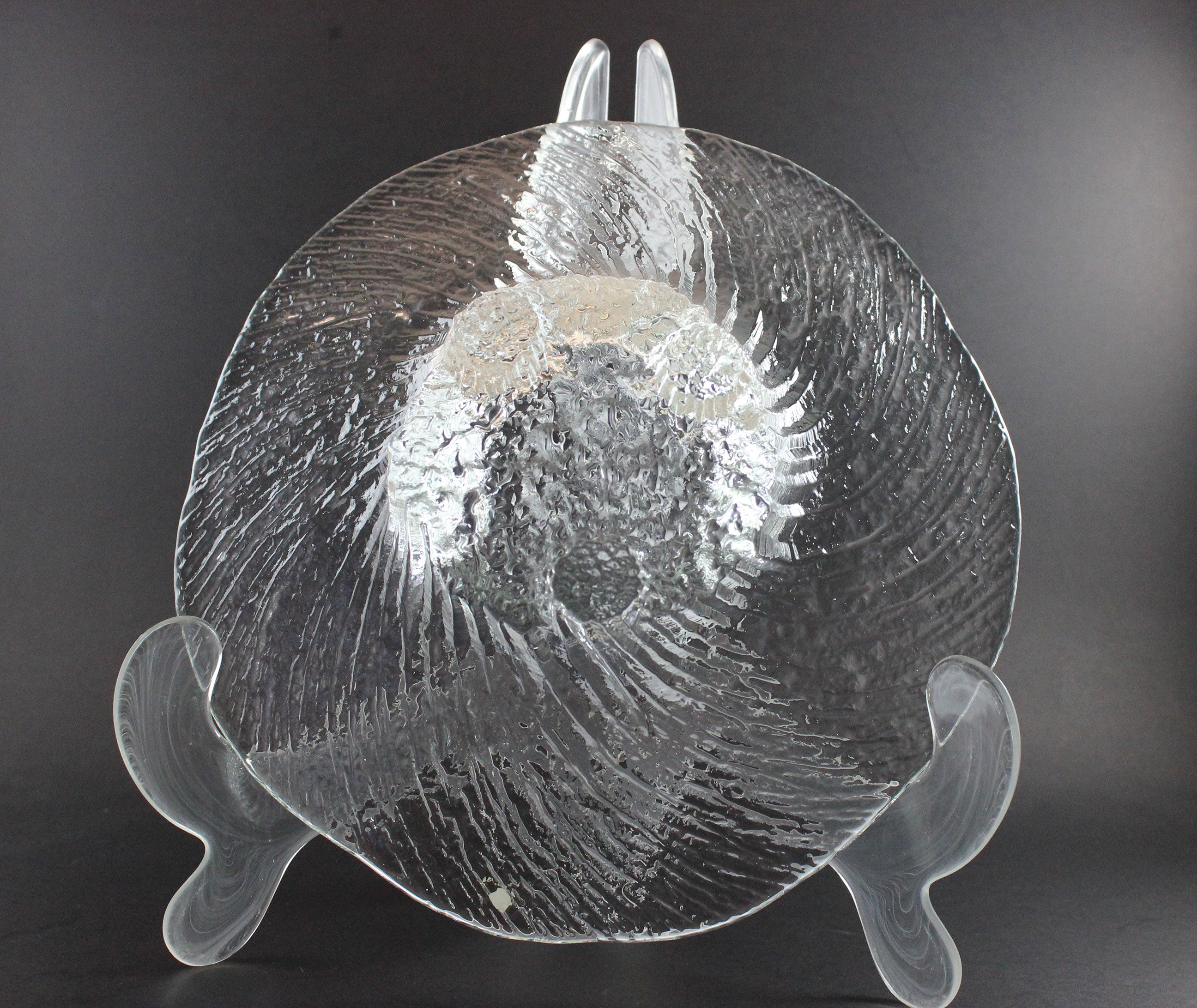 Clear glass footed bowl with textured surface on a dark background