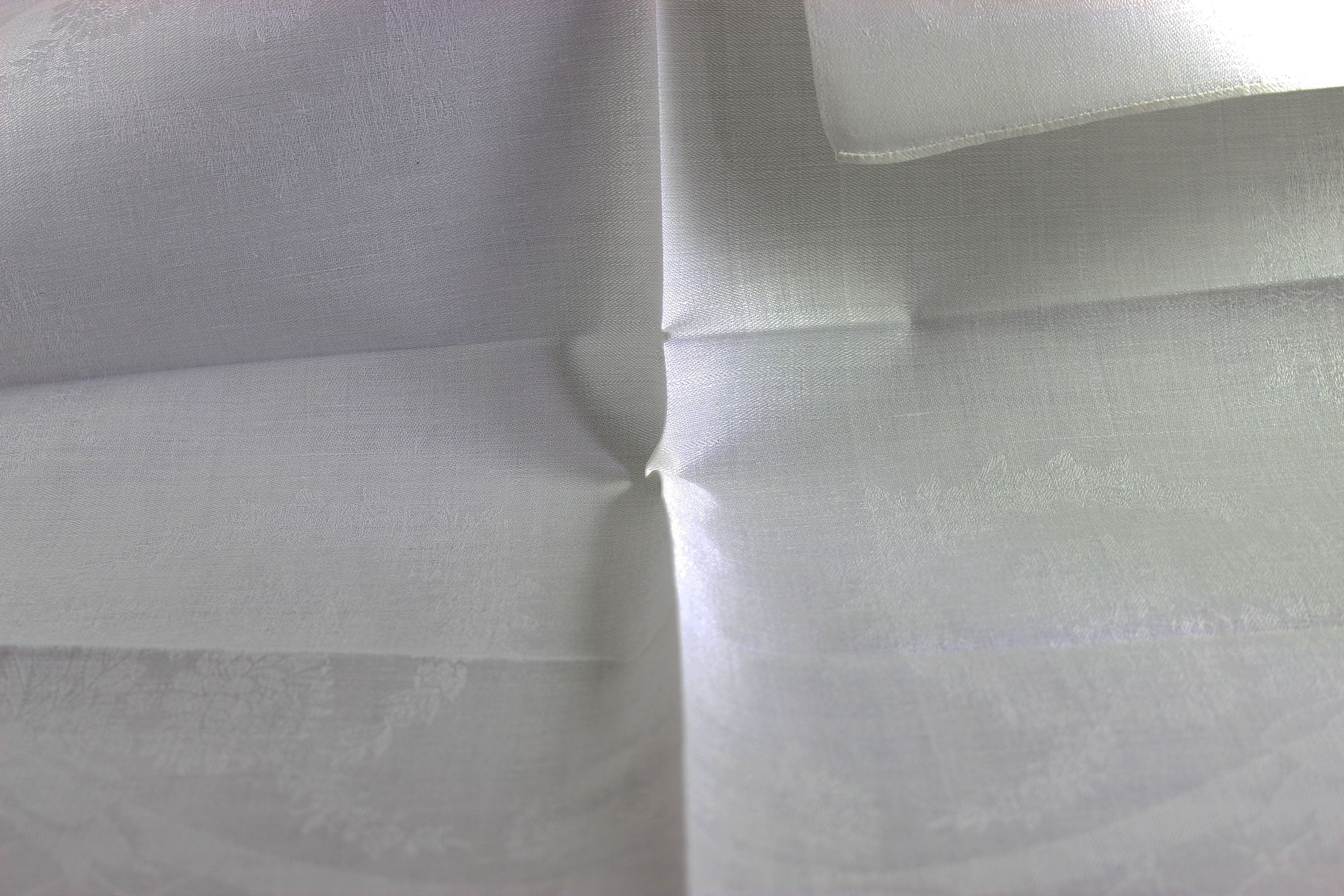 Close-up of white damask linen napkin with a subtle pattern