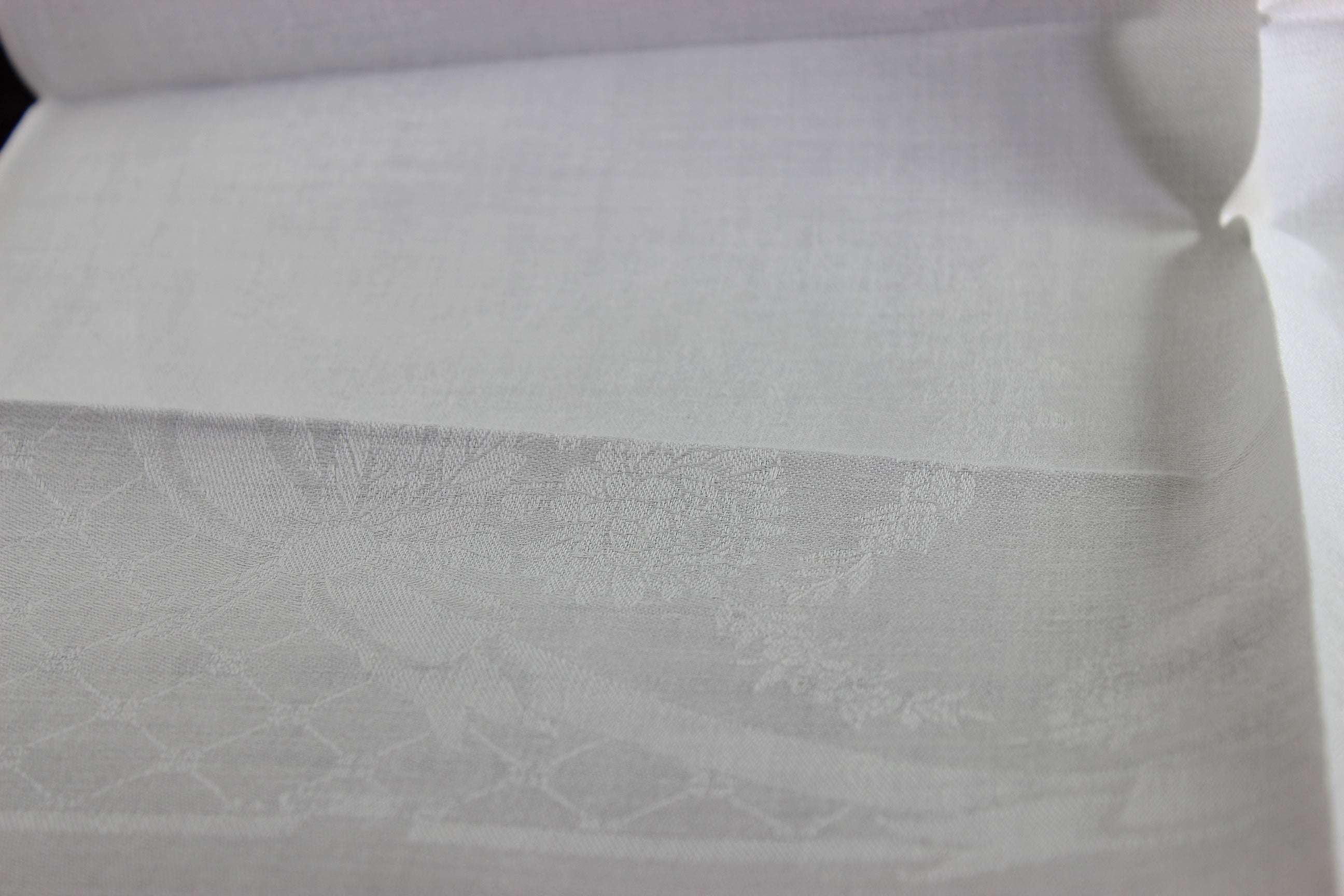 Close-up of white damask linen napkin with a subtle pattern