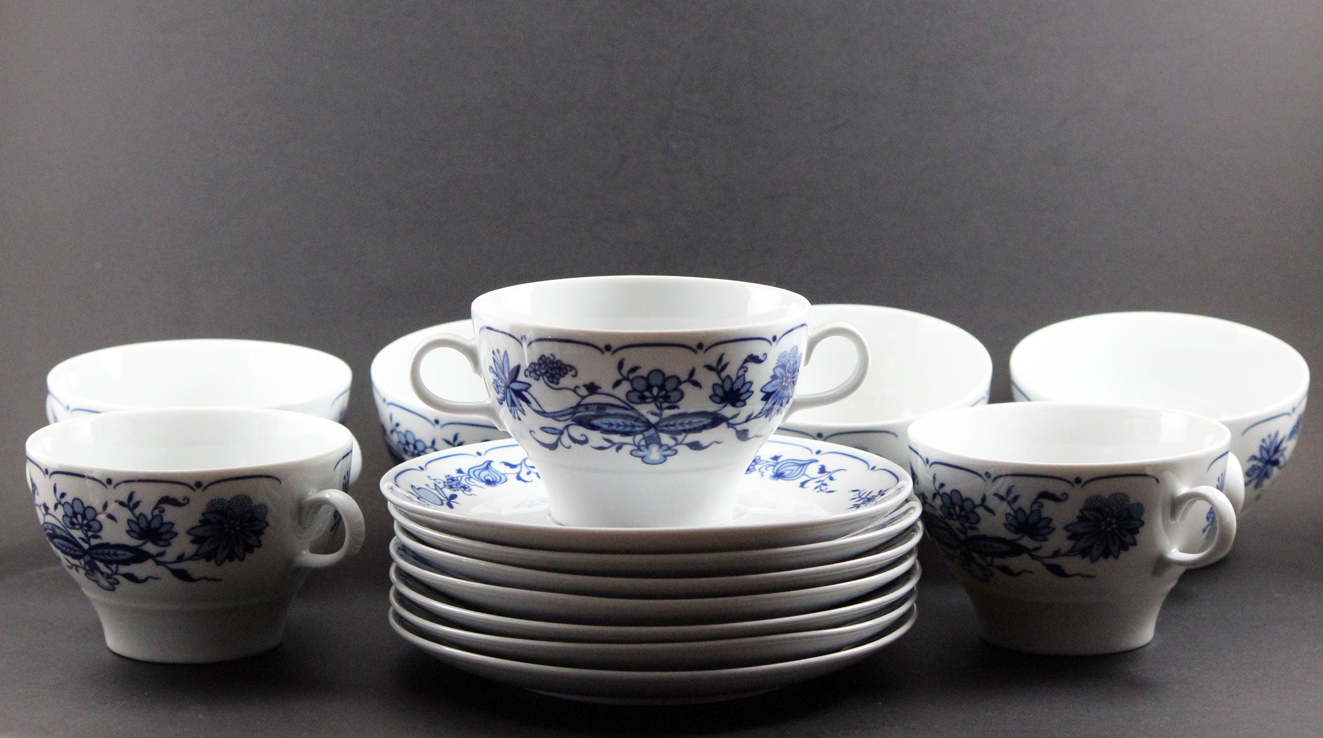 Set of white porcelain soup bowls with blue floral patterns on a gray background