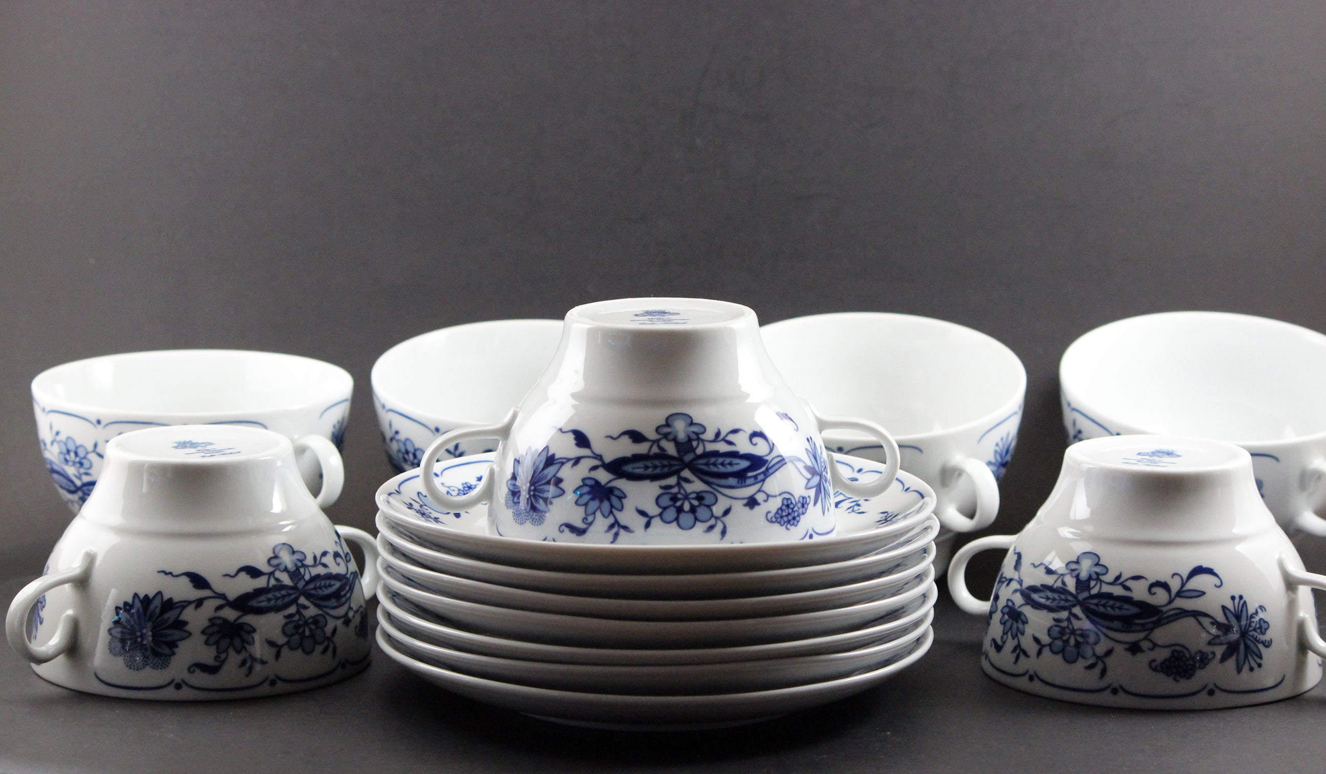 Set of white porcelain soup bowls with blue floral patterns on a gray background