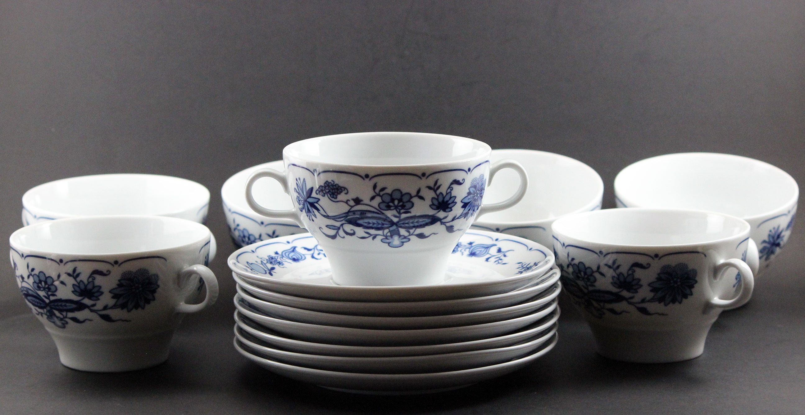 Set of white porcelain soup bowls with blue floral patterns on a gray background