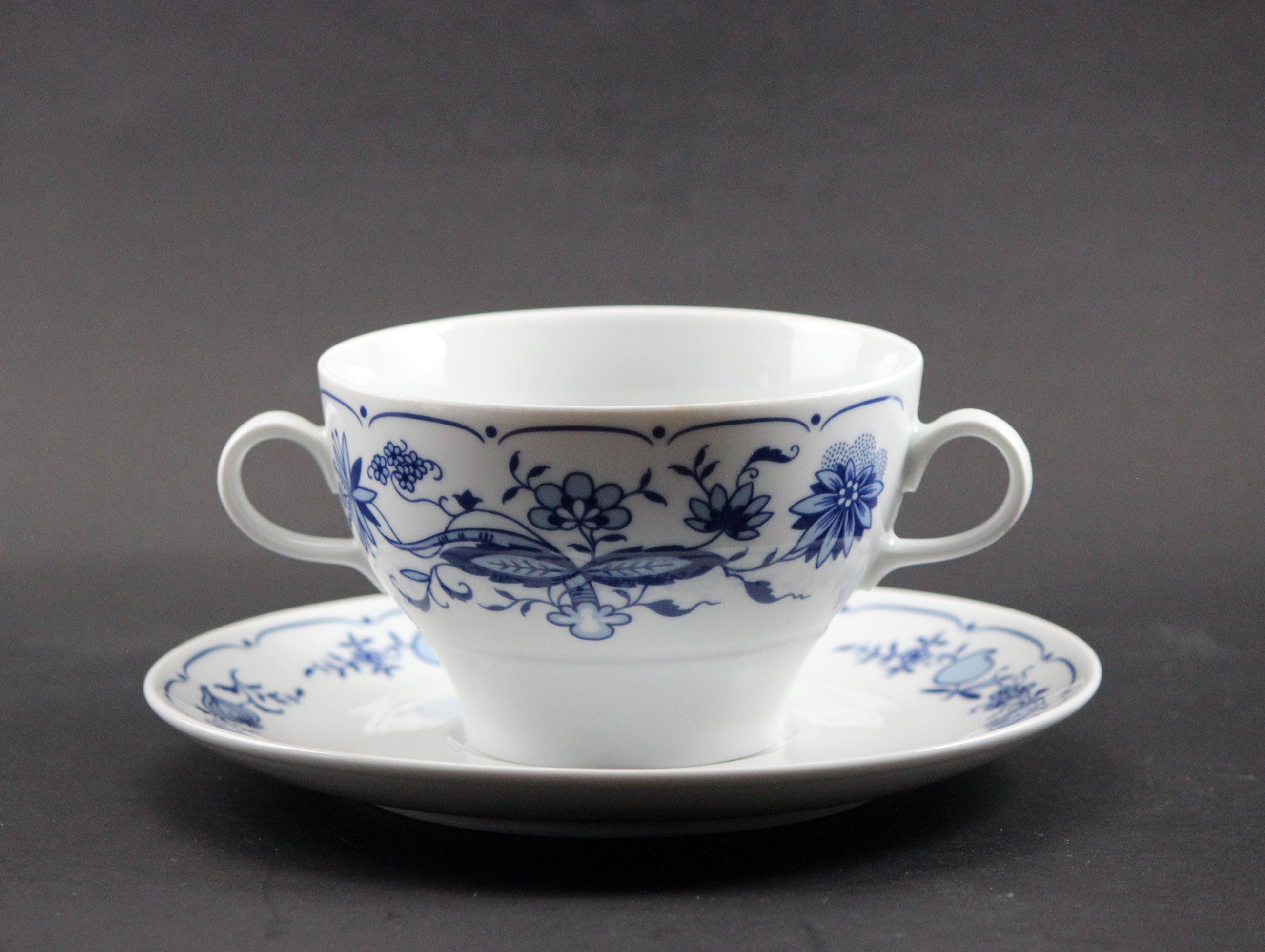 Set of white porcelain soup bowls with blue floral patterns on a gray background