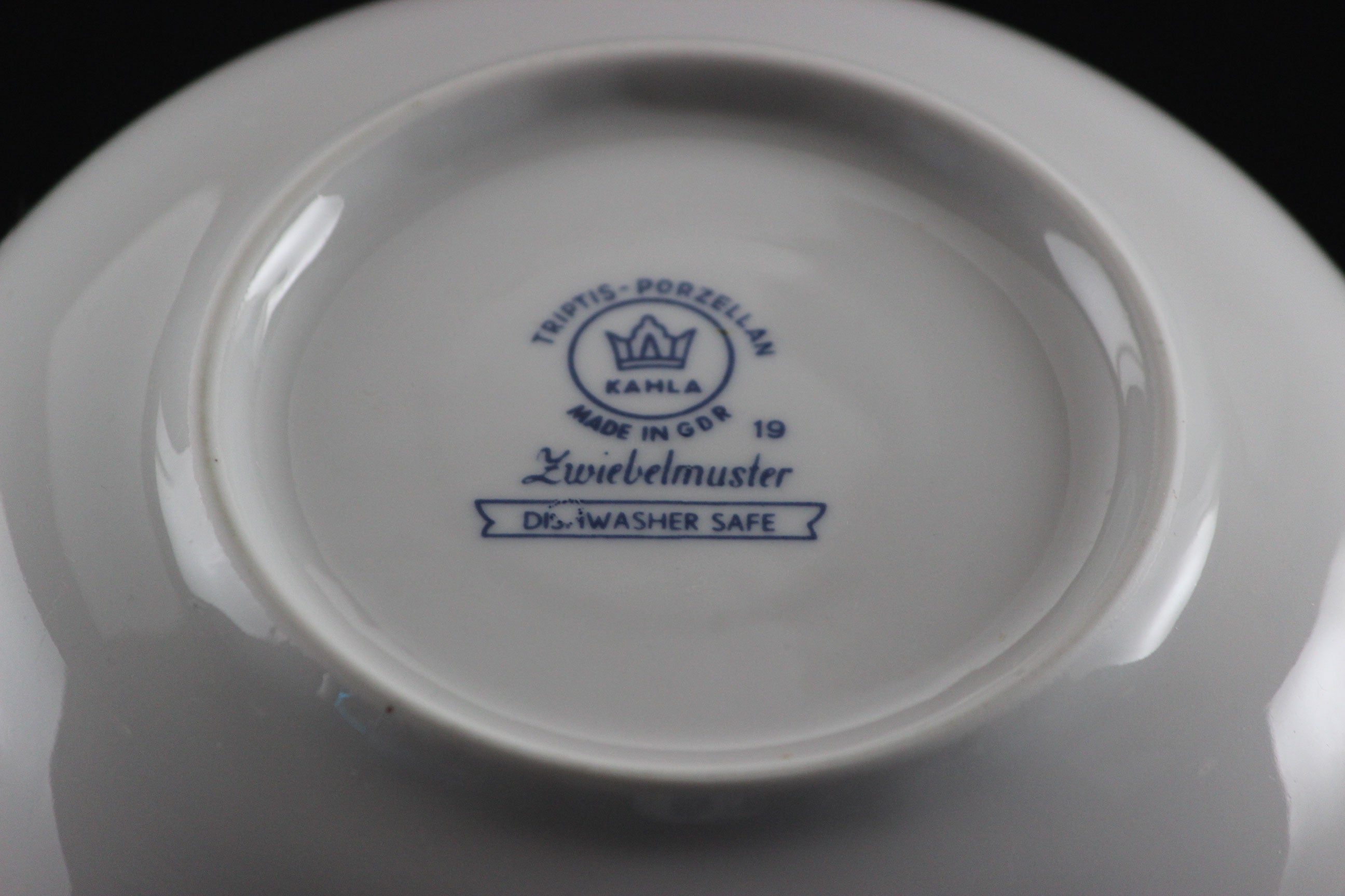 Porcelain teacup and saucer with blue floral patterns on a dark background