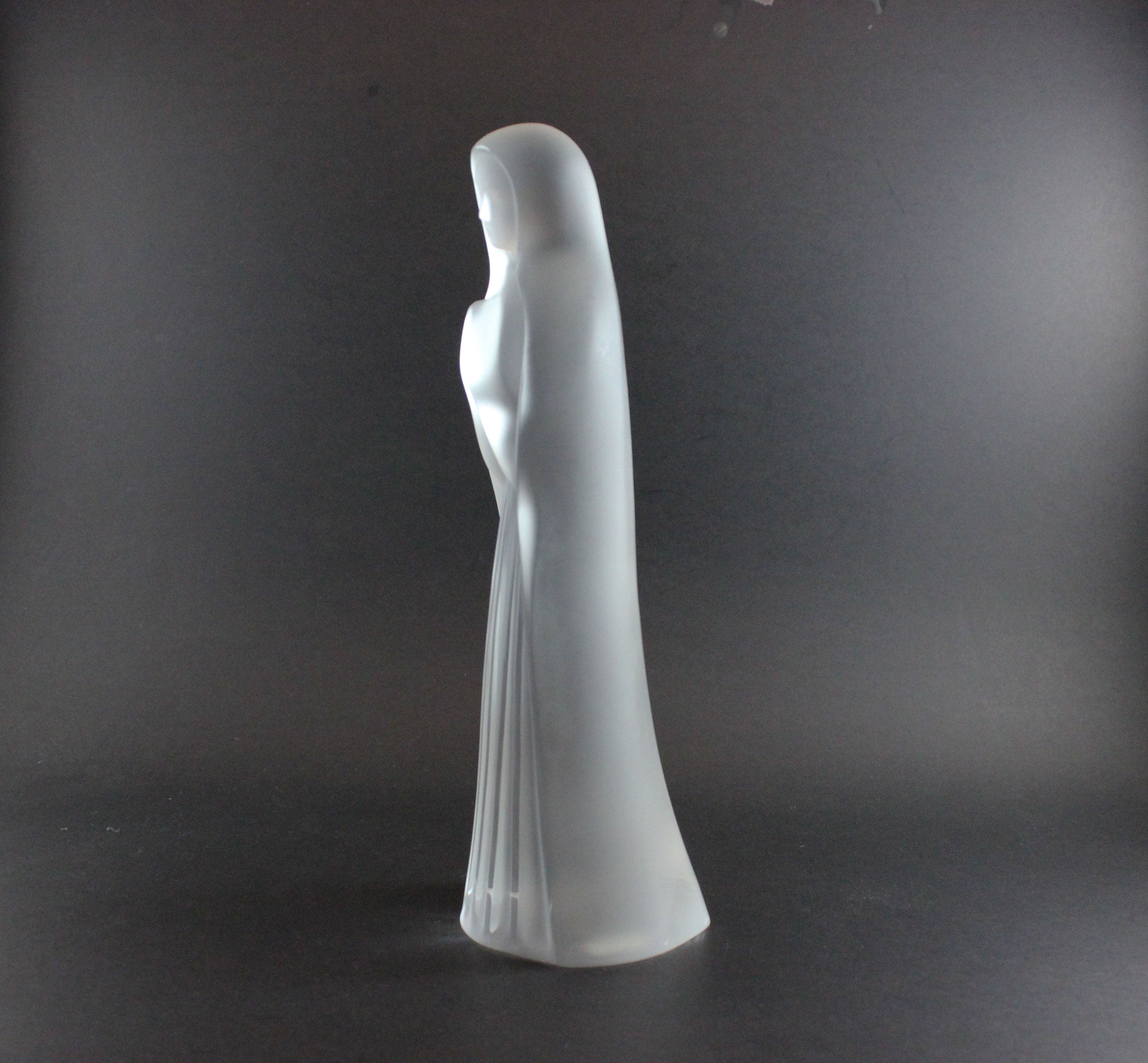 White sculpture of a draped figure on a dark gray background
