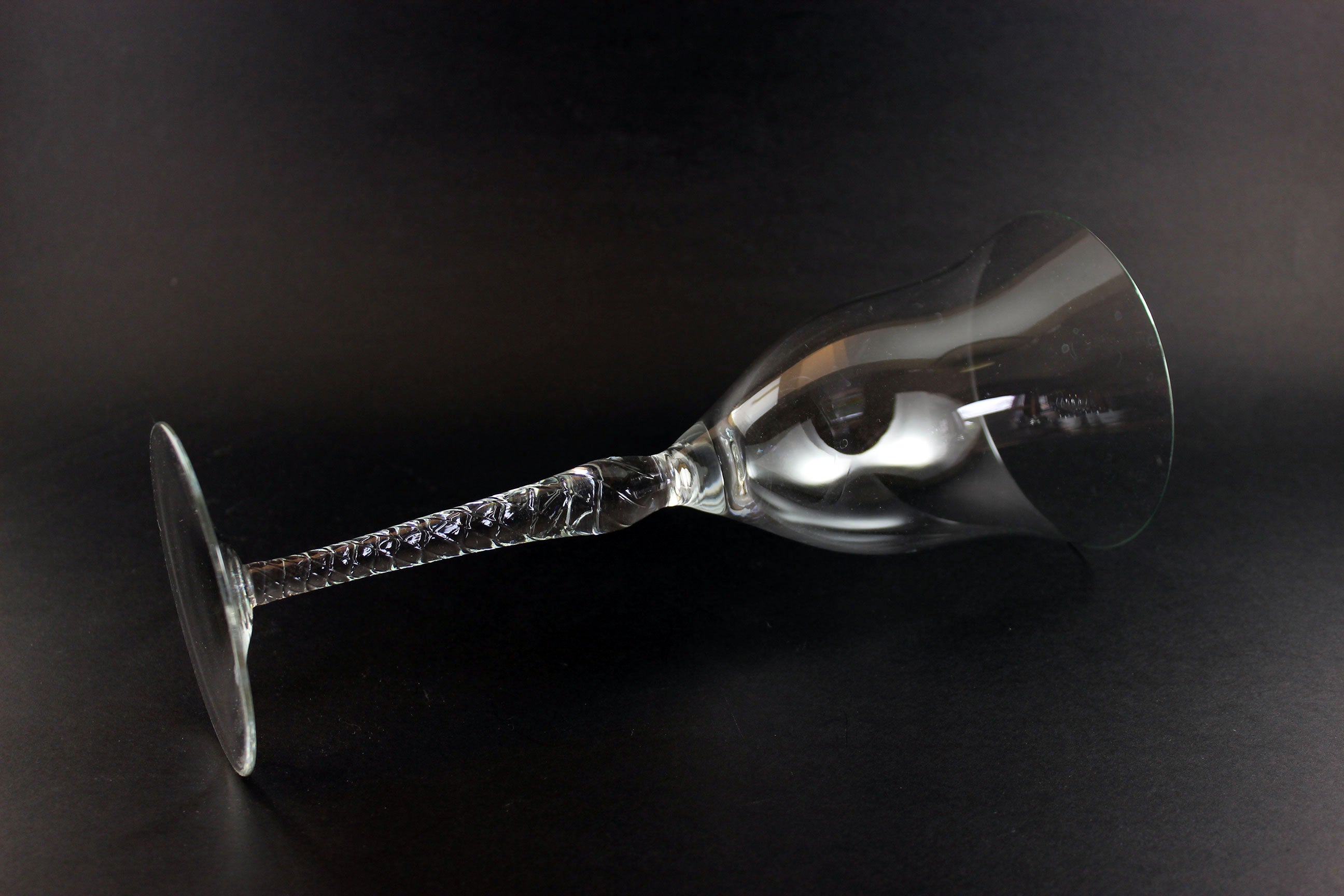 Clear glass wine glass with a long stem on a black background
