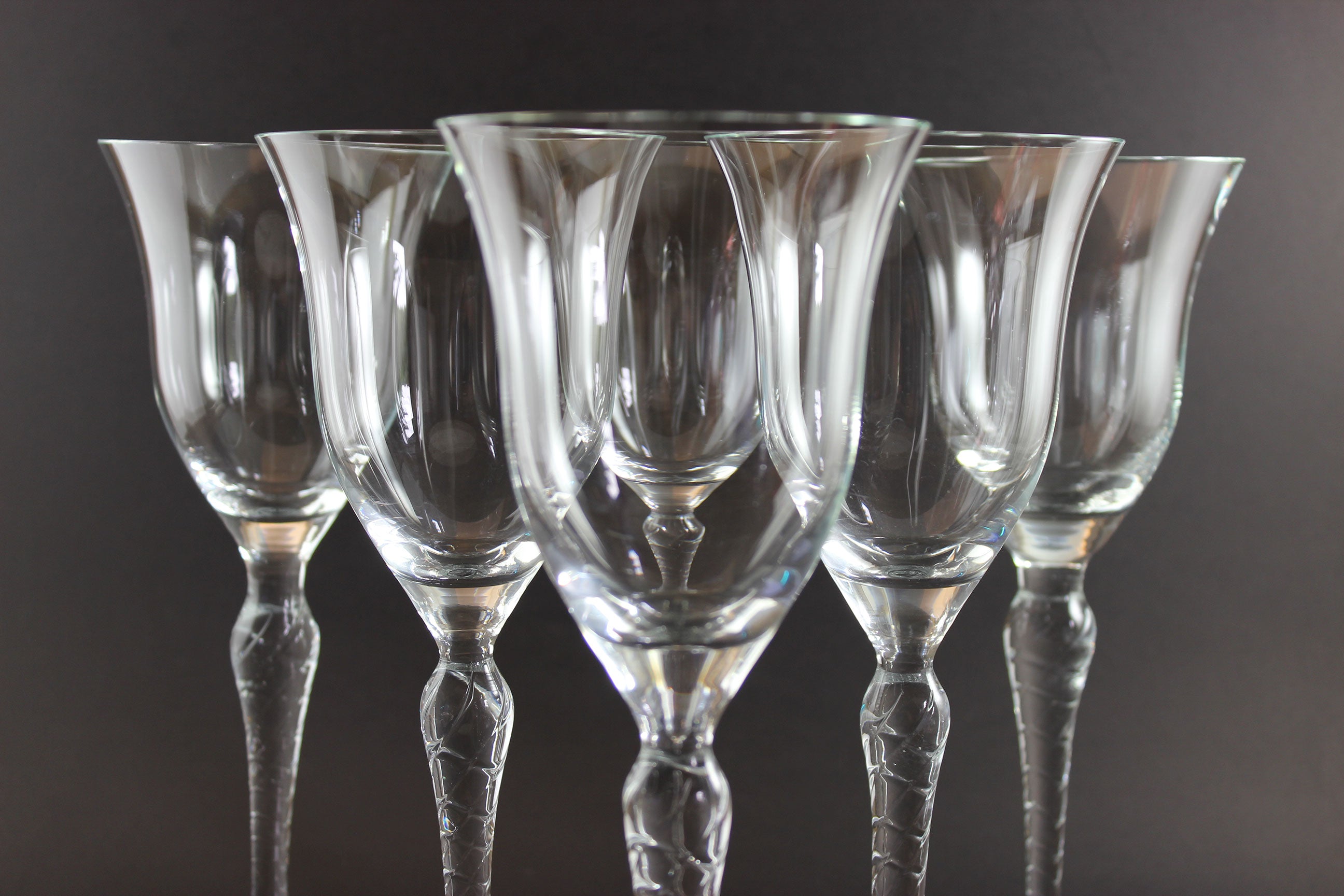 Set of six clear wine glasses on a dark background