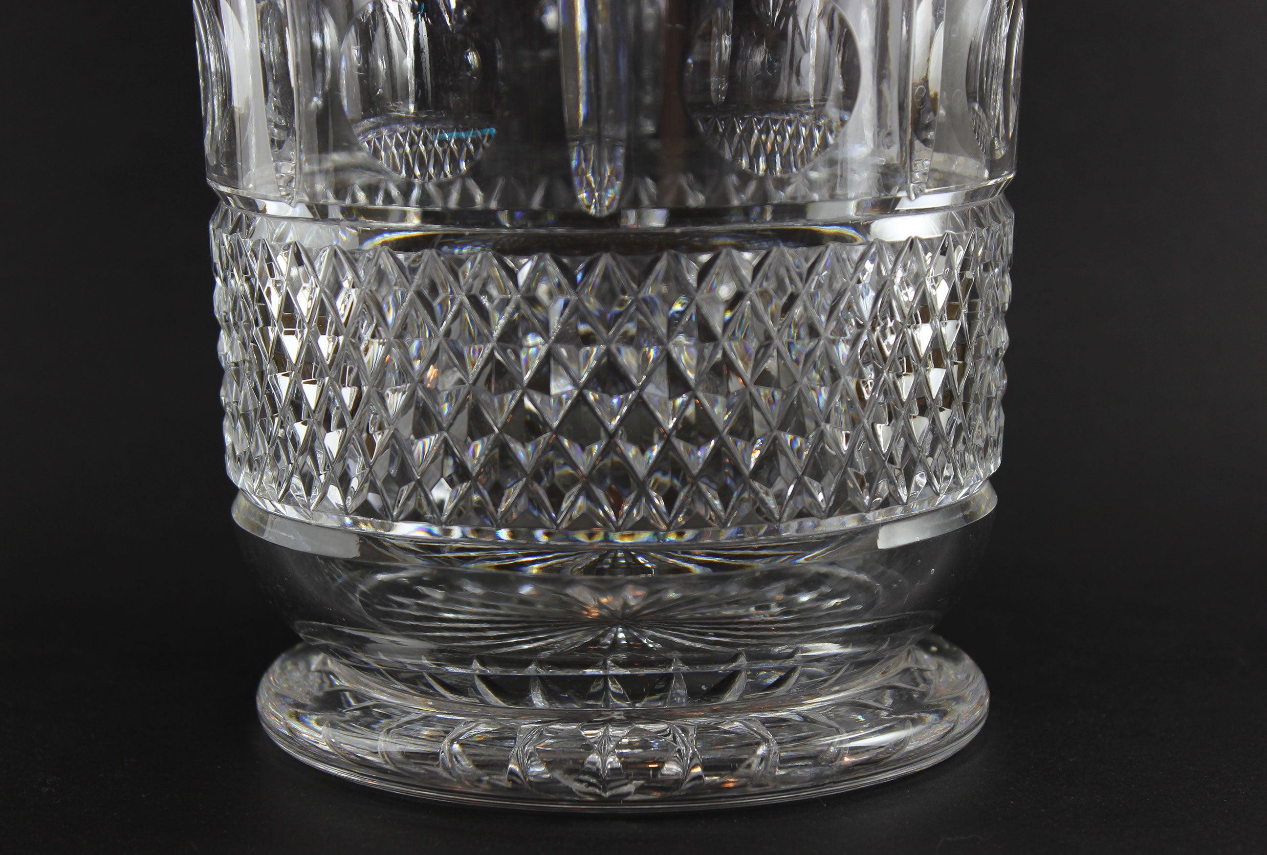 Close-up of a clear crystal bowl or vase with diamond cut pattern on a black background