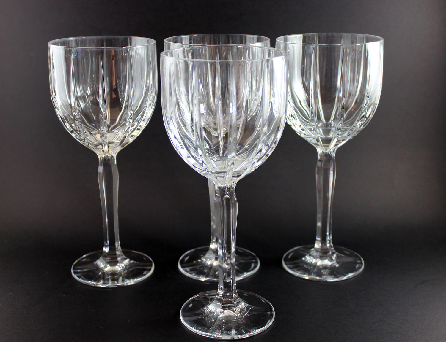 Set of four clear glass wine glasses on a dark background