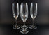 Four Mikasa Stephanie Pattern clear champagne flutes on a black background