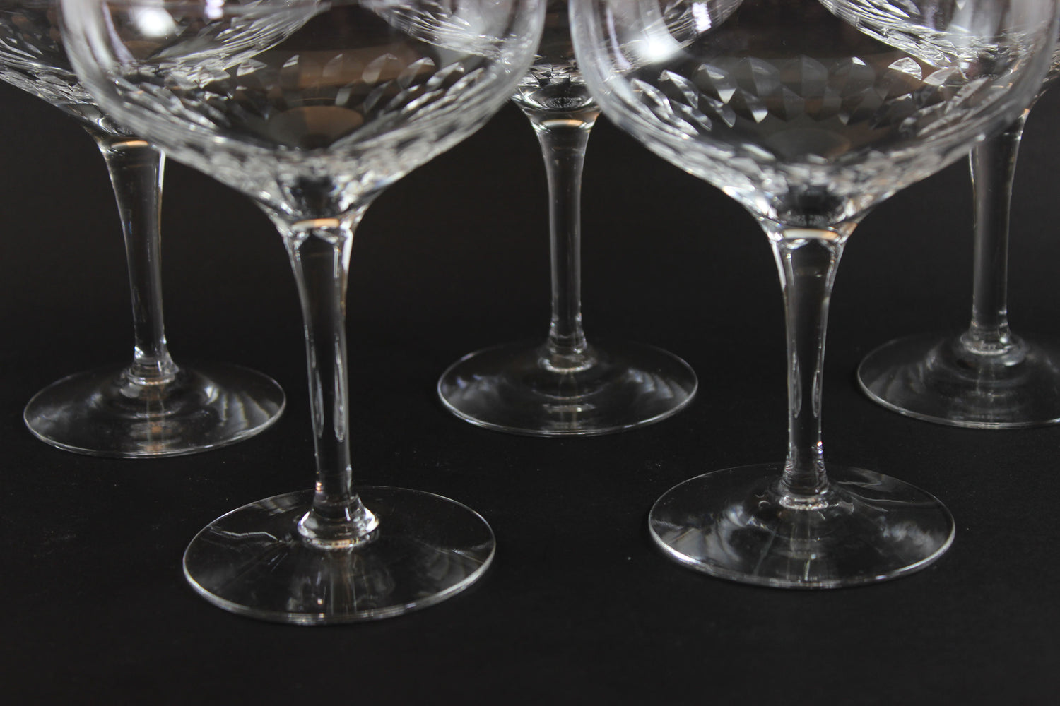 Set of six clear champagne coupe glasses on a black background