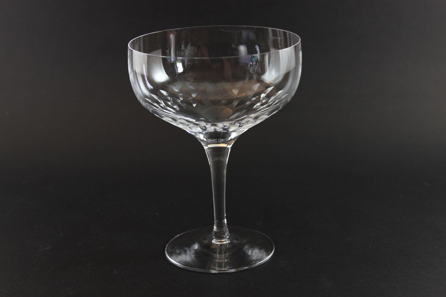 Set of six clear champagne coupe glasses on a black background