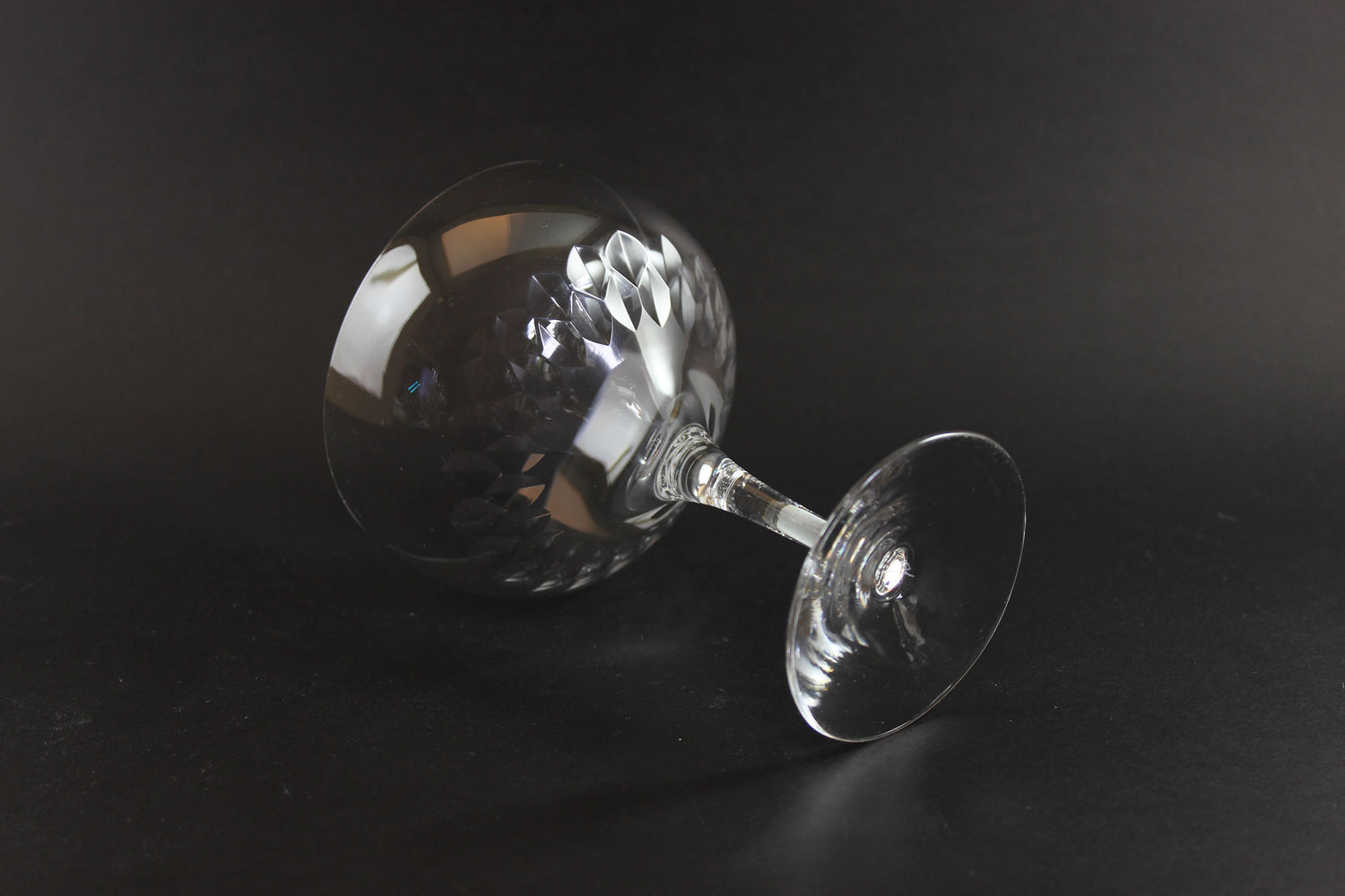 Set of six clear champagne coupe glasses on a black background