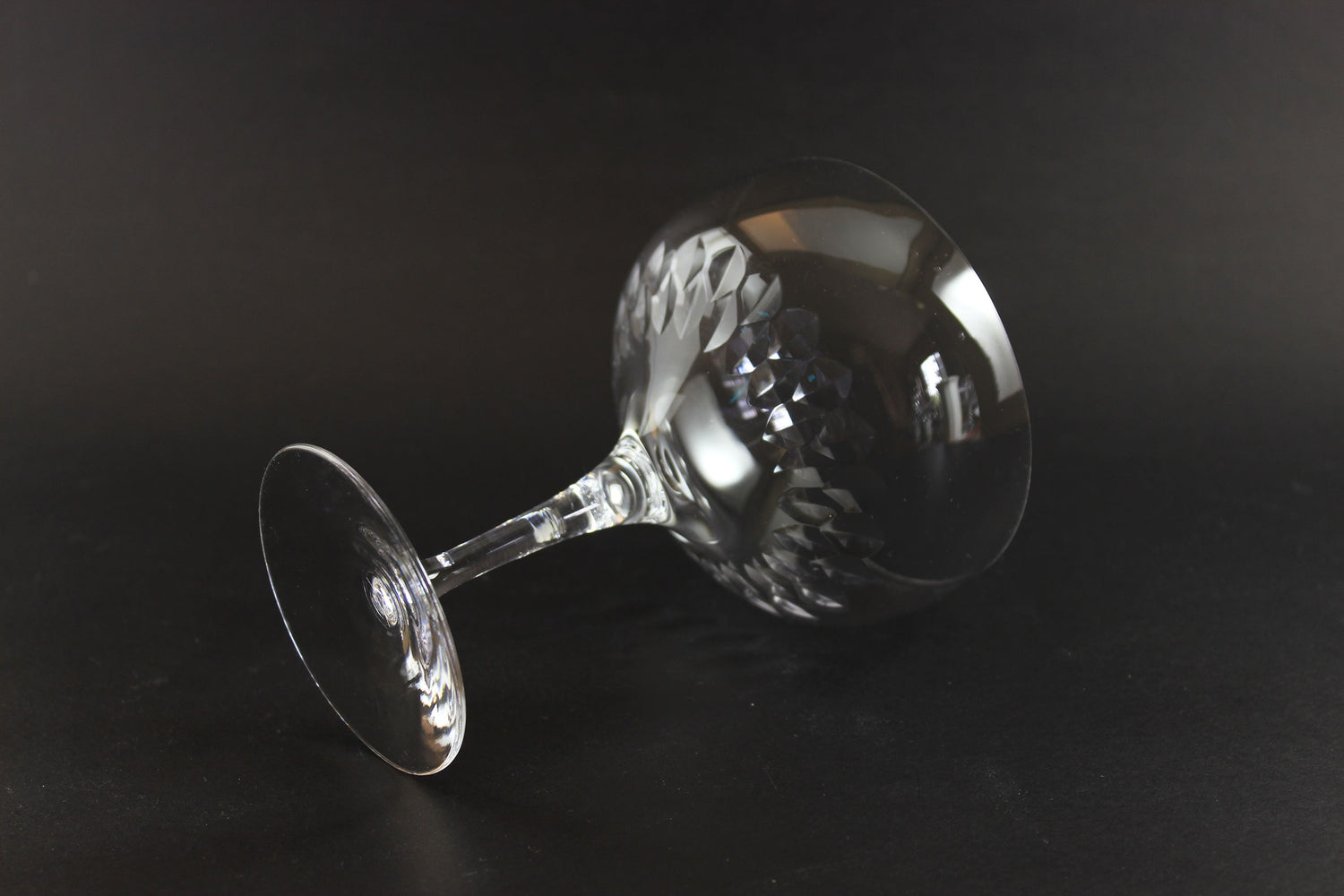 Set of six clear champagne coupe glasses on a black background