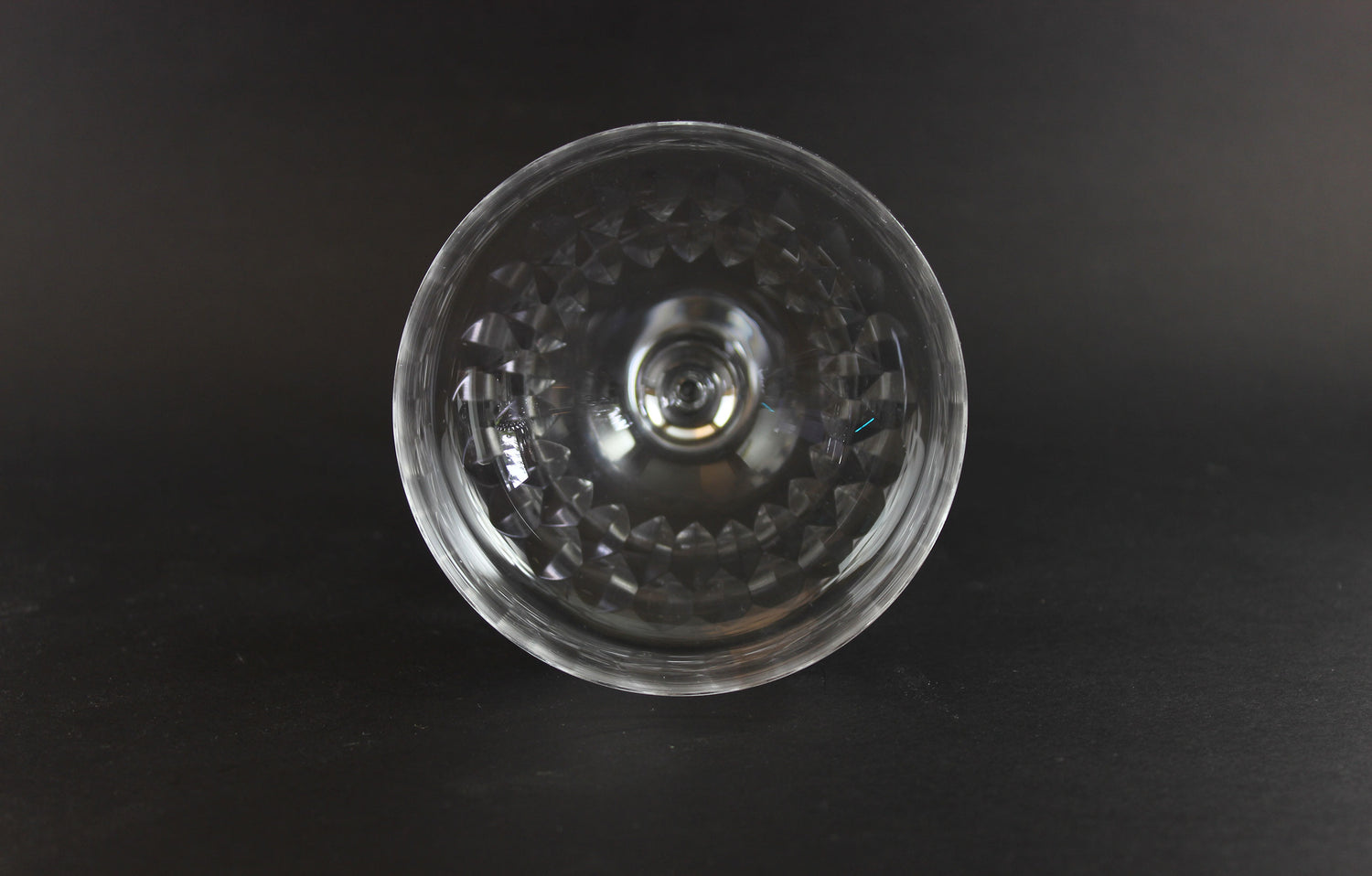 Set of six clear champagne coupe glasses on a black background