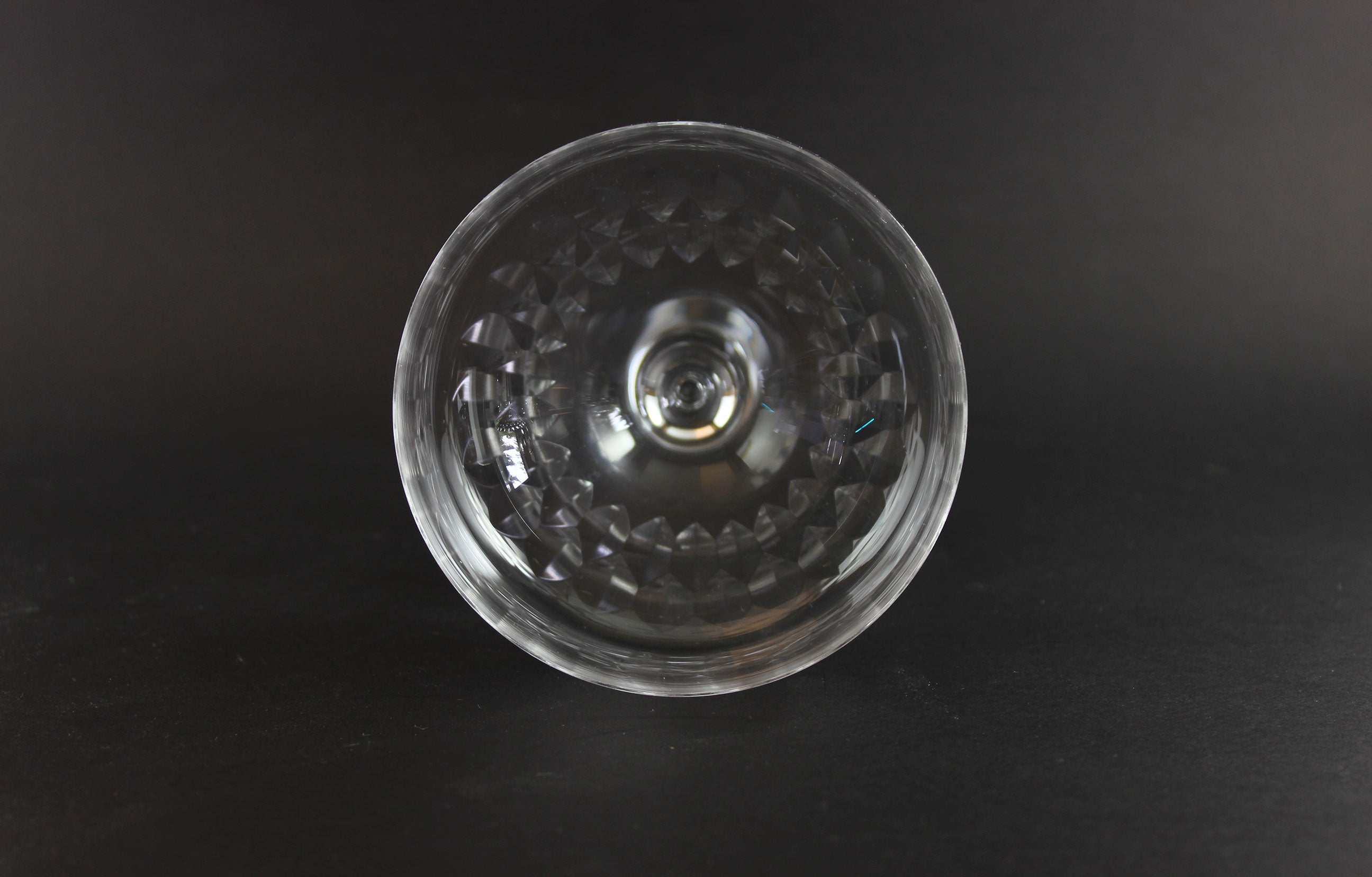 Set of six clear champagne coupe glasses on a black background