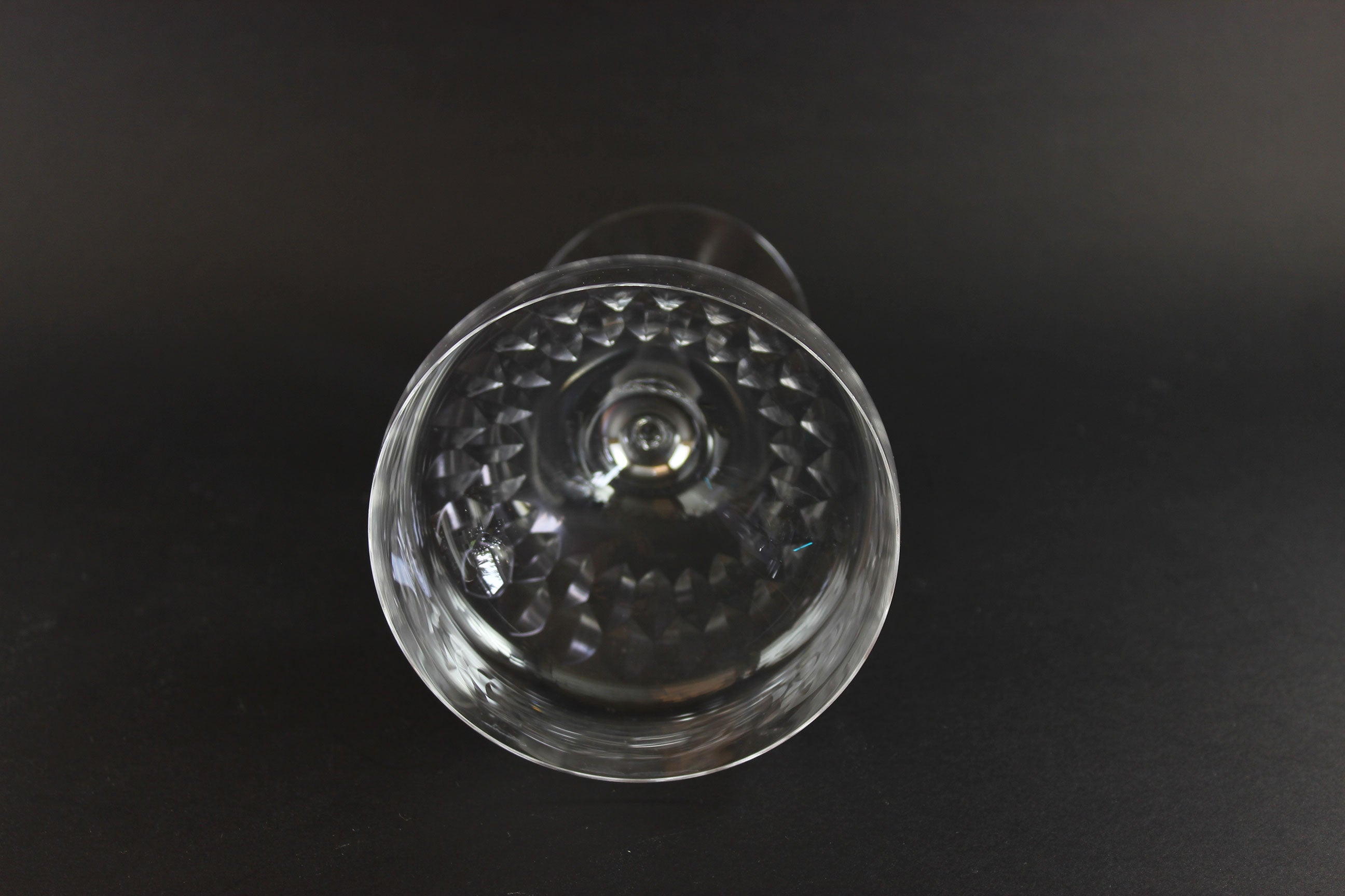 Set of six clear champagne coupe glasses on a black background