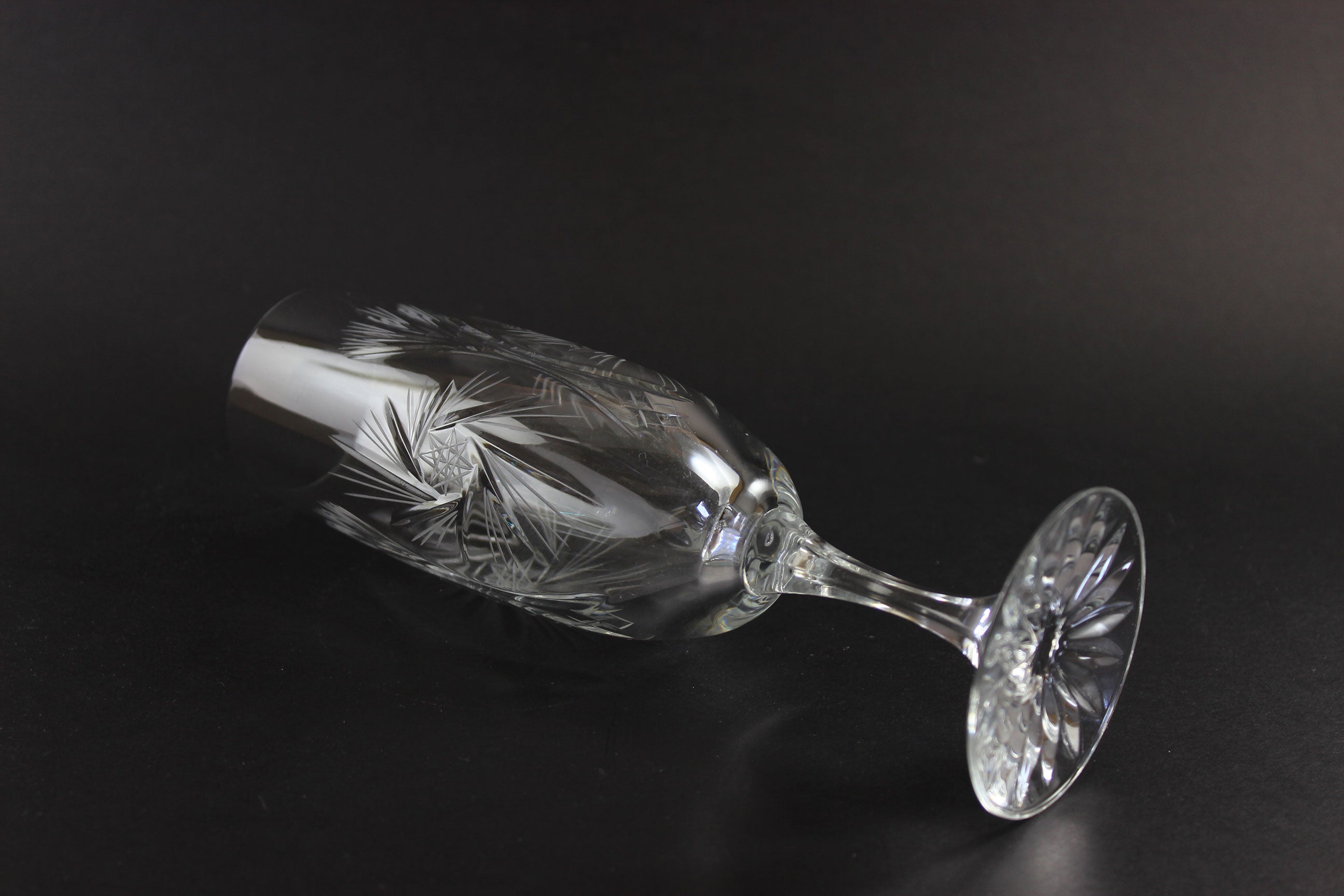 Two crystal champagne flutes with cut pinwheel design on a black background