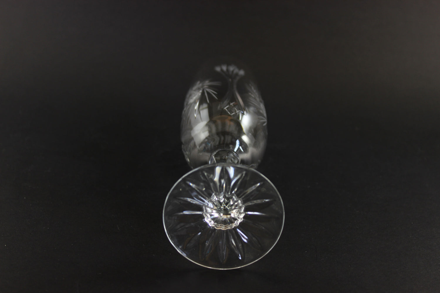Two crystal champagne flutes with cut pinwheel design on a black background