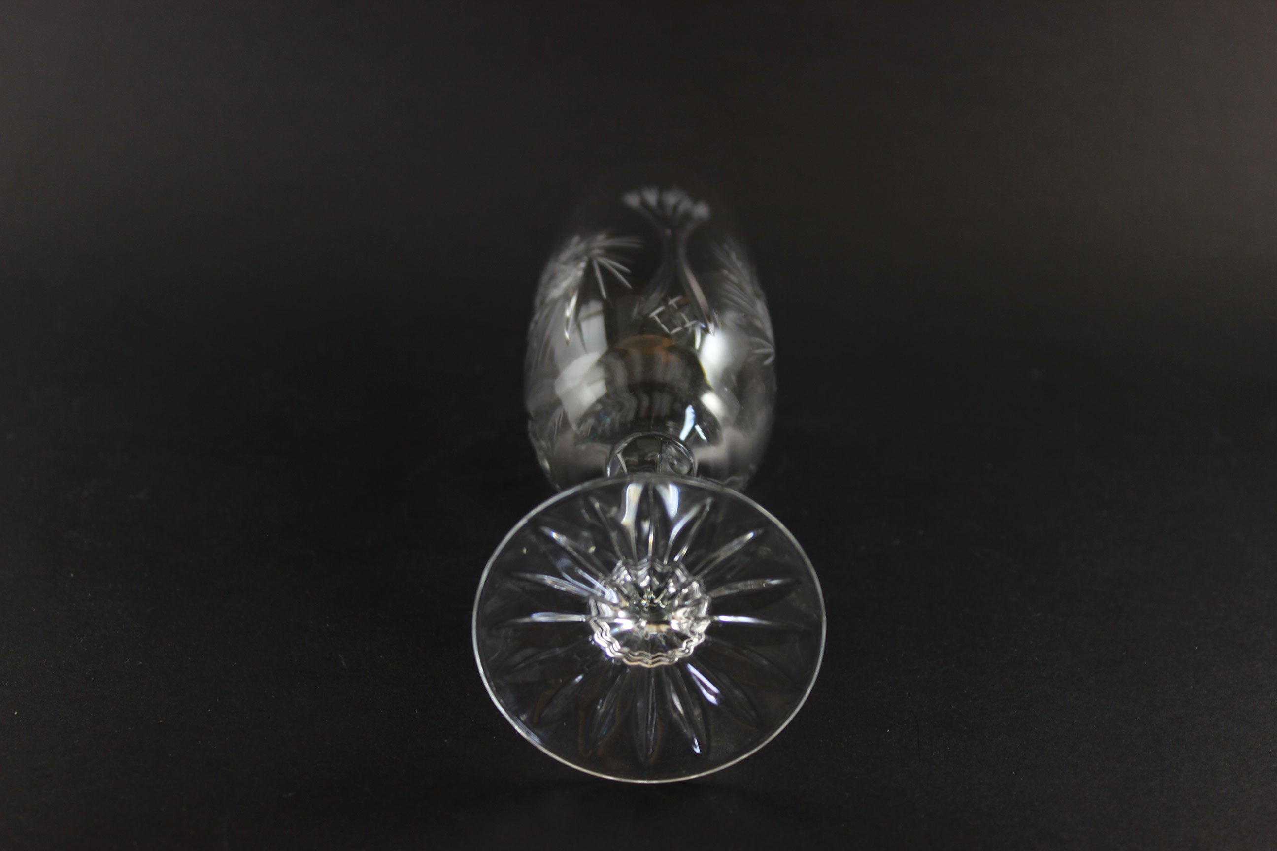 Two crystal champagne flutes with cut pinwheel design on a black background