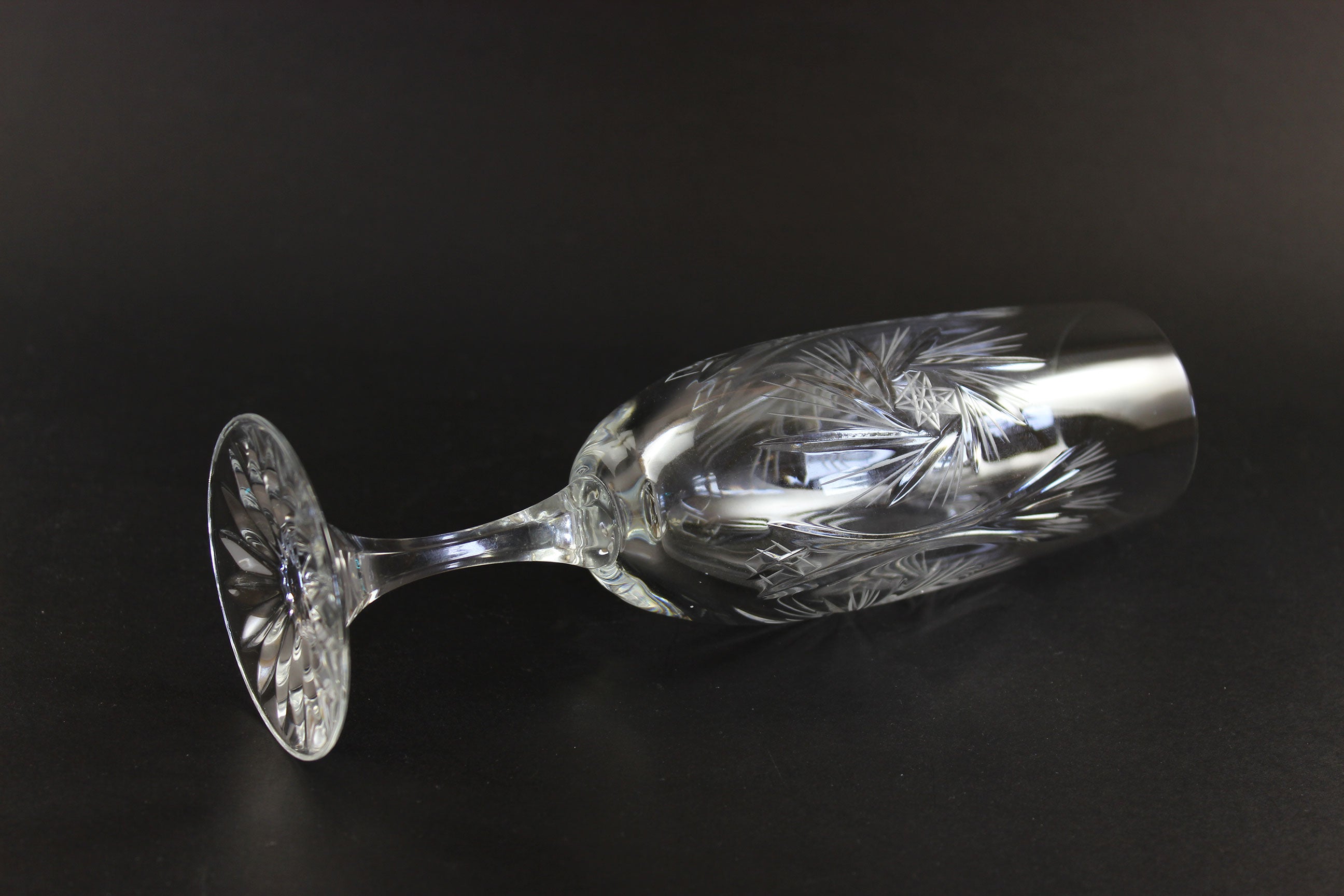 Two crystal champagne flutes with cut pinwheel design on a black background