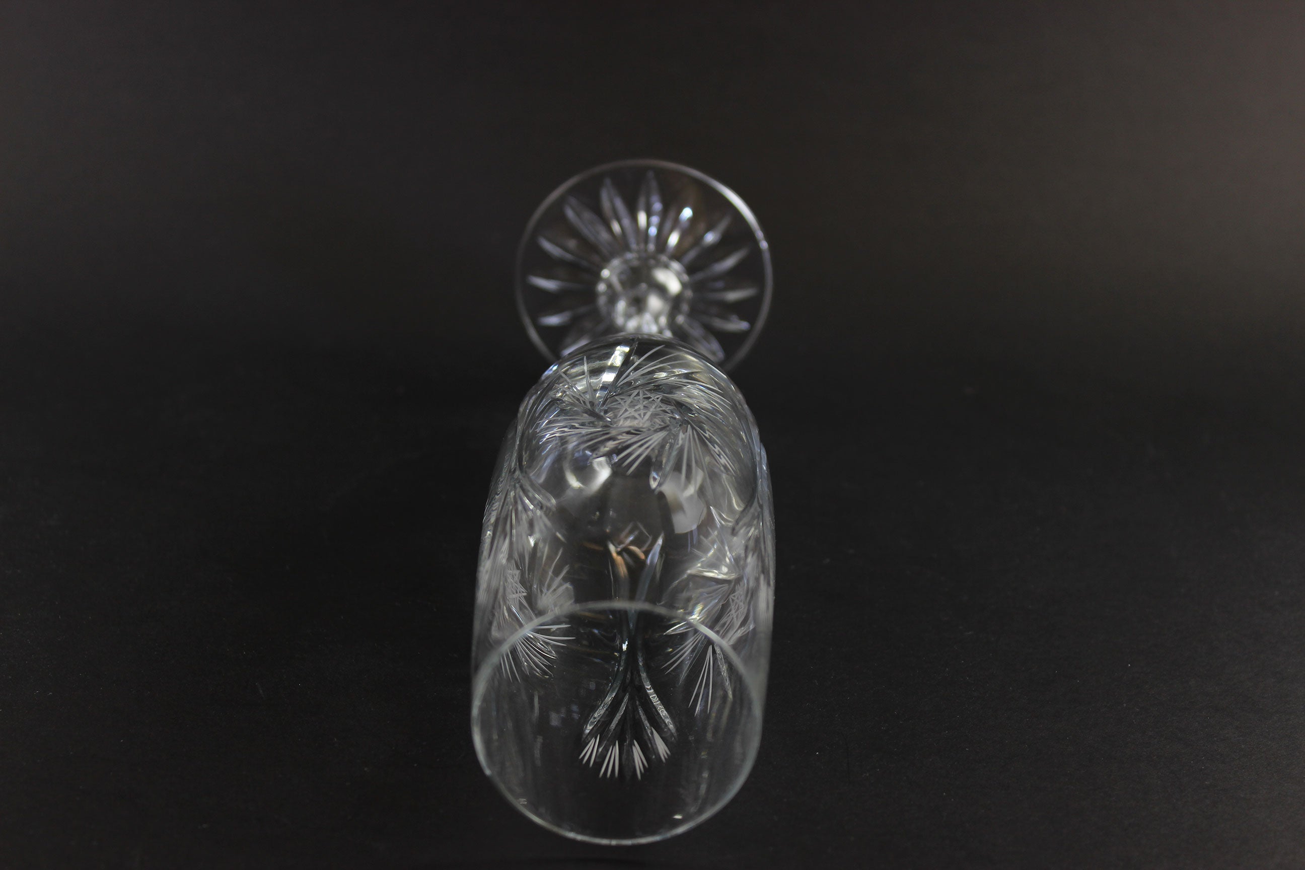 Two crystal champagne flutes with cut pinwheel design on a black background